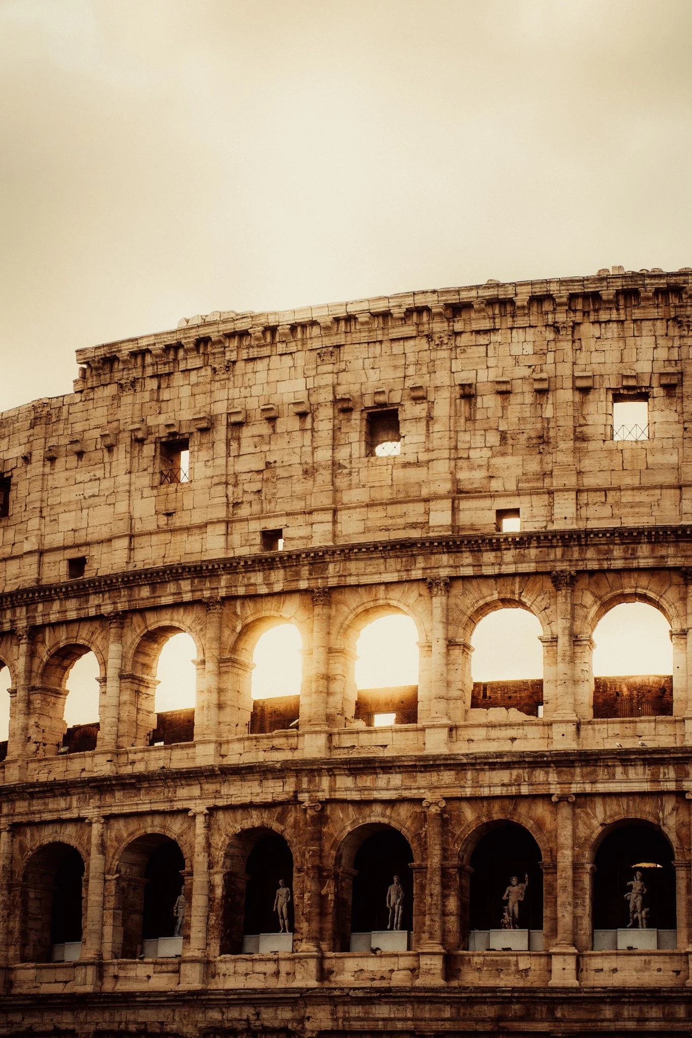 Close-up of the Roman Colosseum with sunlight shining through the arches.