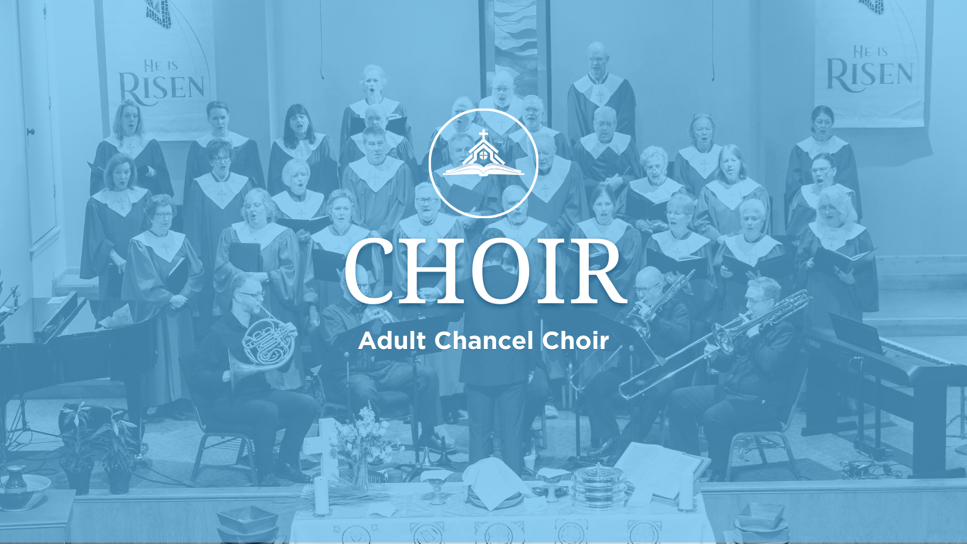 A choir performing on stage in a church, with people holding music sheets, a piano, and musical instruments, and a red banner with white text reading 'angel CHOIR'.
