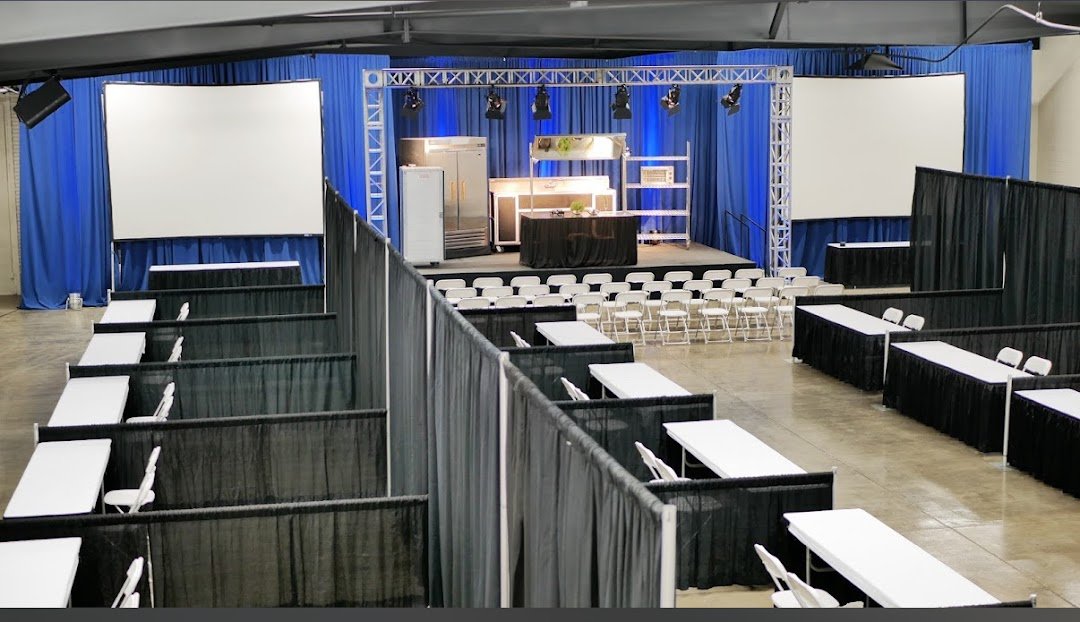 Pipe and drape backdrop installed behind a stage for a corporate event or presentation.