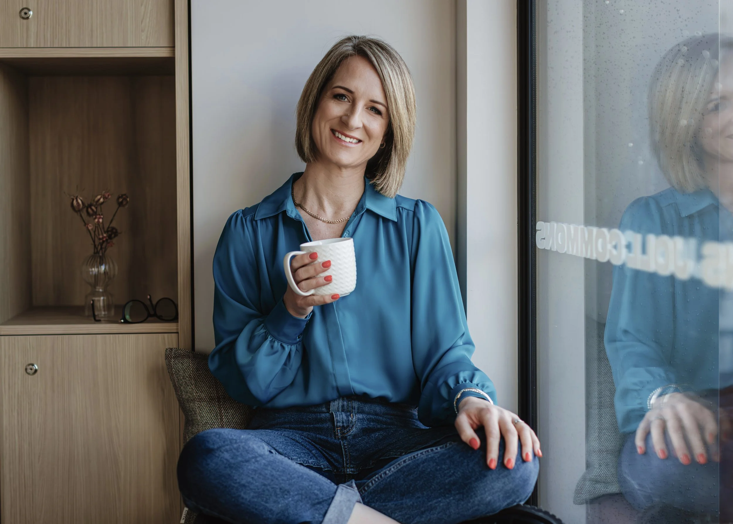 Kylie Parish, designer and owner of Ponder Design Studio, sitting with a coffee cup