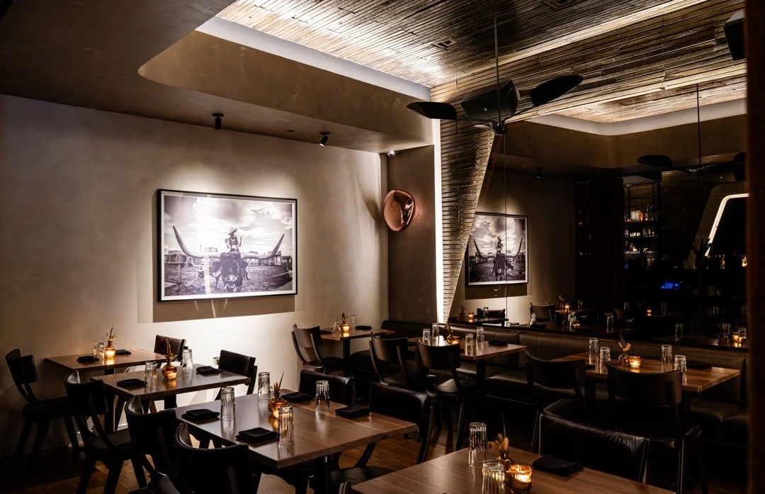 El Che dining room by Siren Betty Design with warm plaster walls, framed ranch photography, mirrored panels, and leather seating.