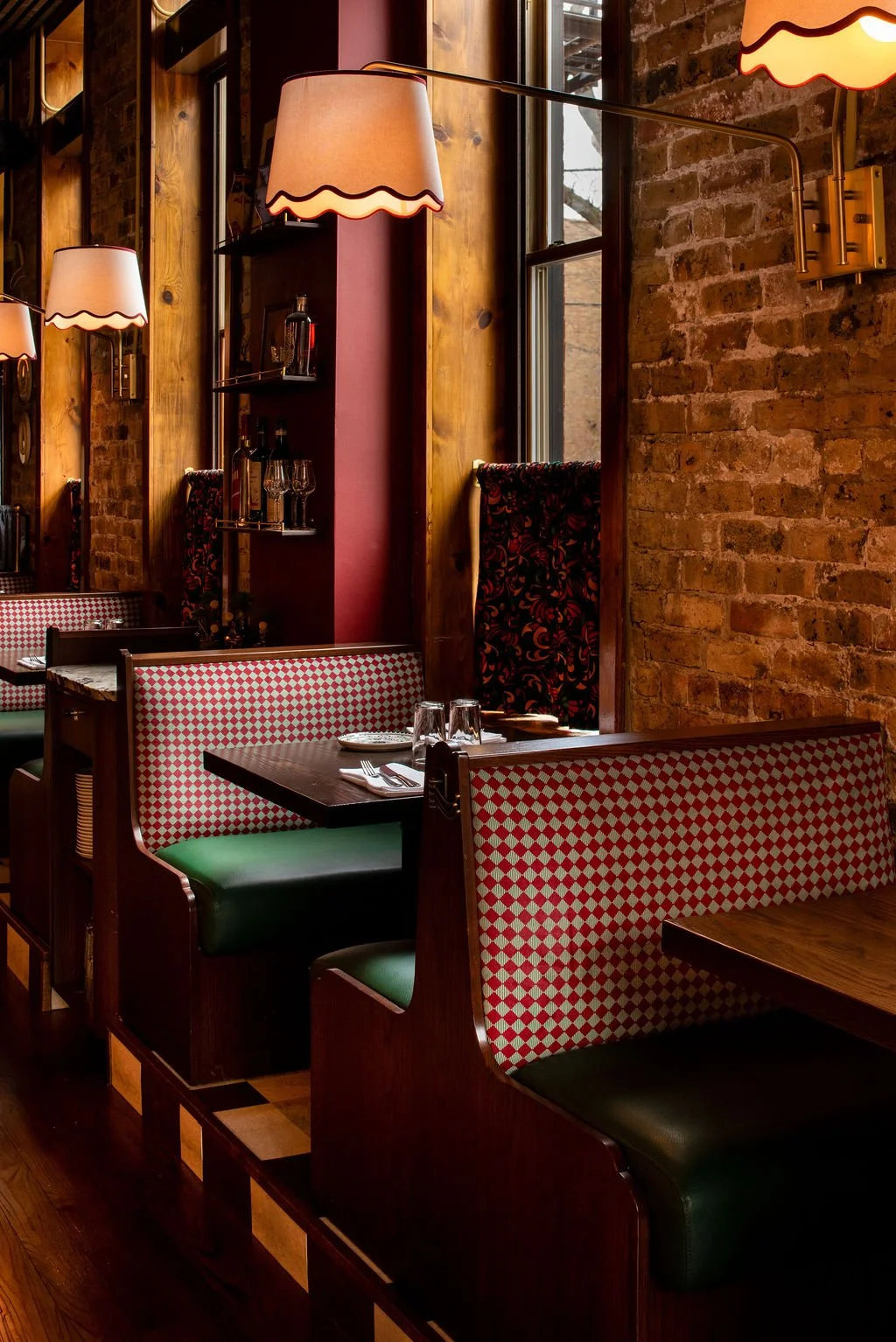 Checkered booth seating with brass sconces and brick walls at Dimmi Dimmi by Siren Betty Design.