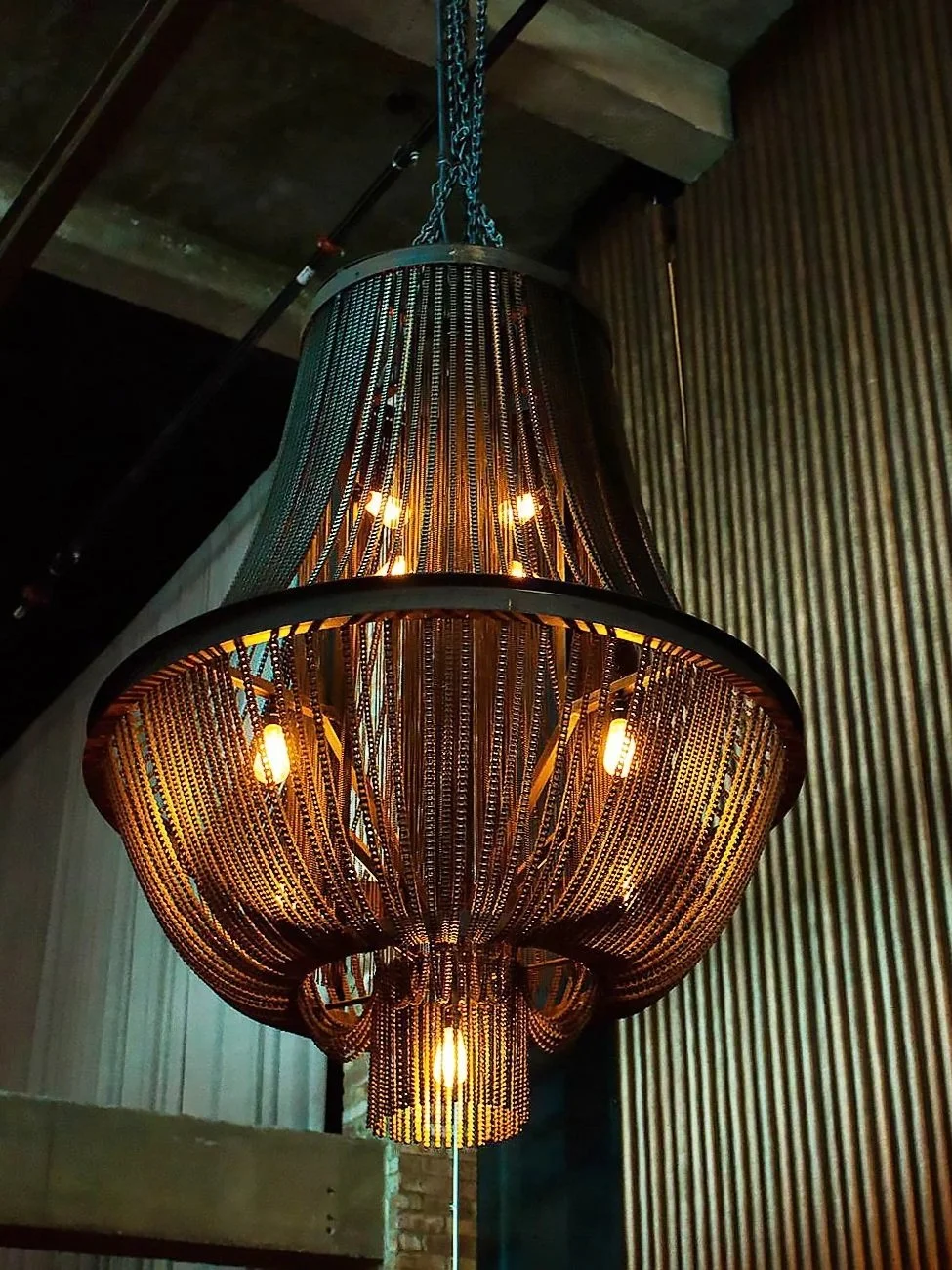 Morgan MFG chain chandelier glowing in an industrial interior with ribbed walls by Siren Betty Design