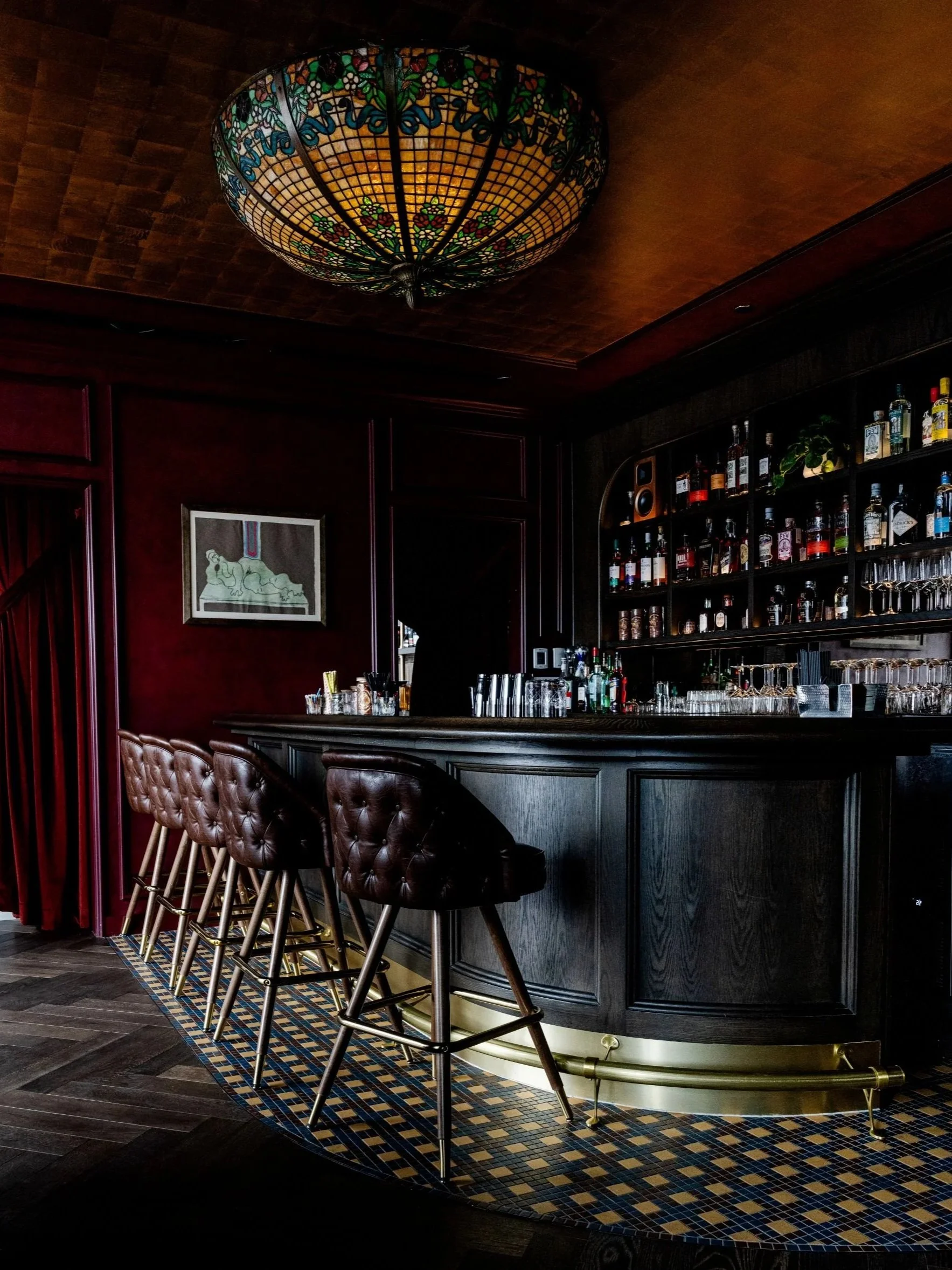 The Anteroom bar with tufted leather stools, mosaic floor and stained-glass light fixture by Siren Betty Design