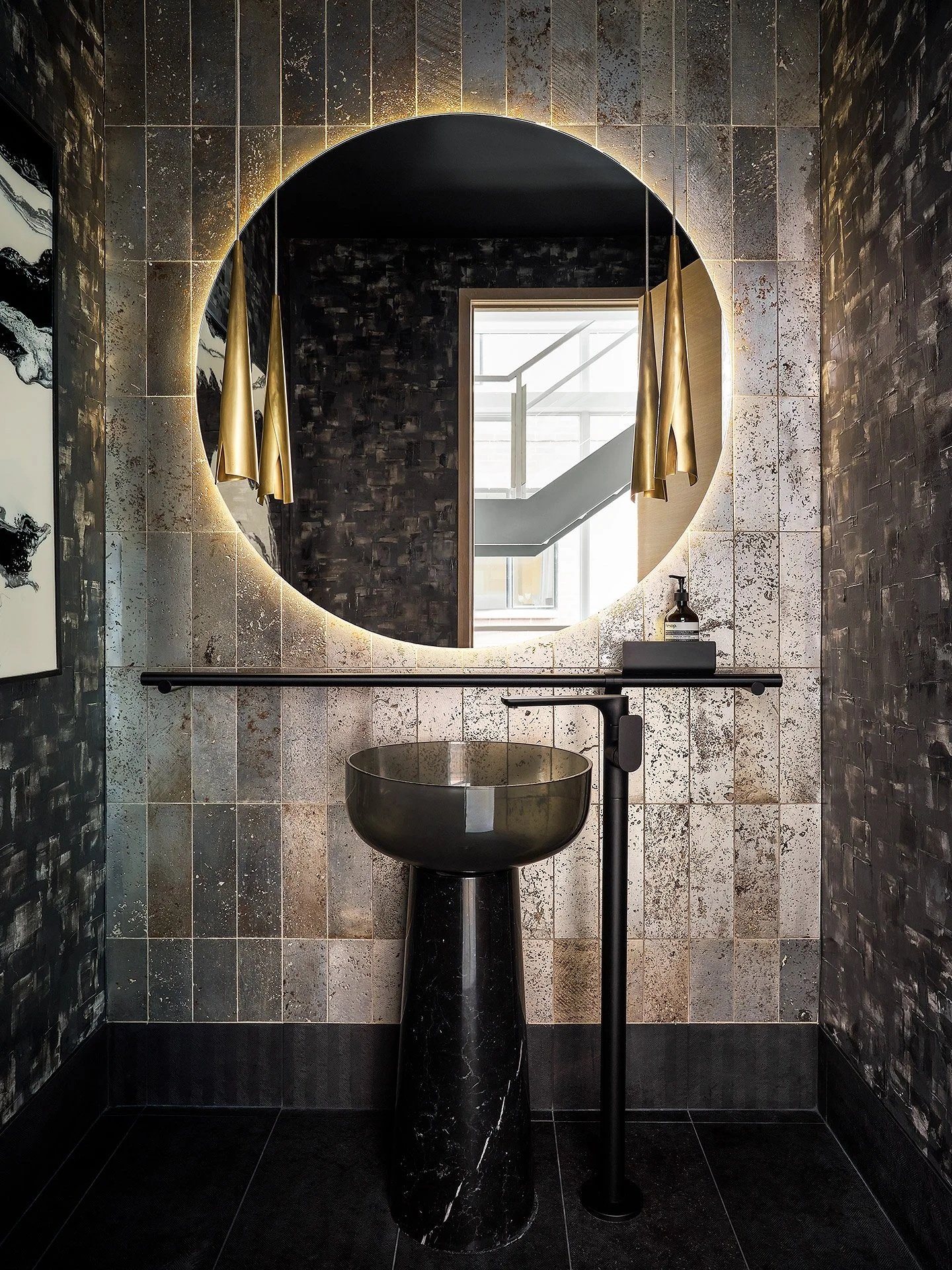 Private residence powder room with glowing round mirror, pedestal sink and textured tile by Siren Betty Design