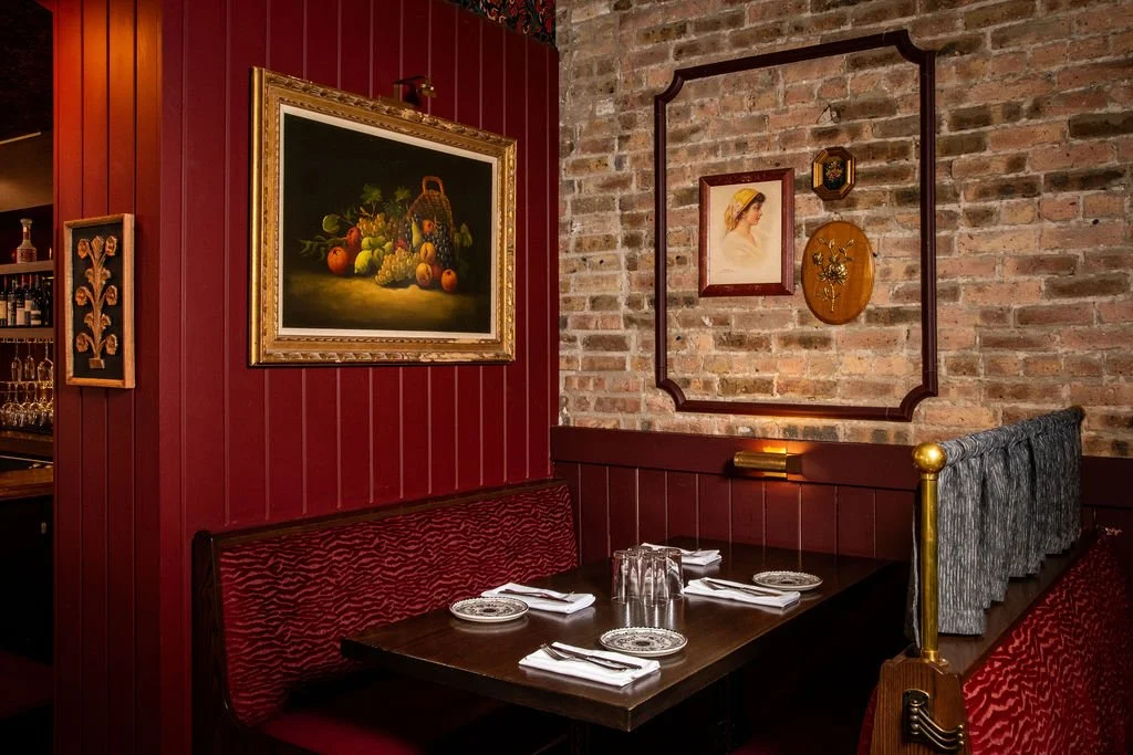 Banquette seating with framed artwork and brick wall at Dimmi Dimmi by Siren Betty Design.