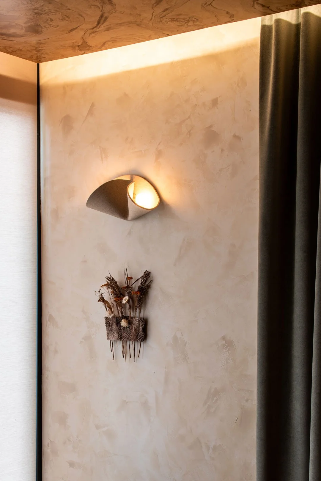 Sculptural wall sconce, textured plaster, and burl-inspired ceiling detail inside Burl restaurant by Siren Betty Design.