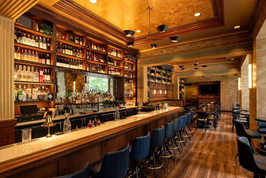 Eaves restaurant bar and dining room with custom millwork, warm lighting and blue seating by Siren Betty Design.