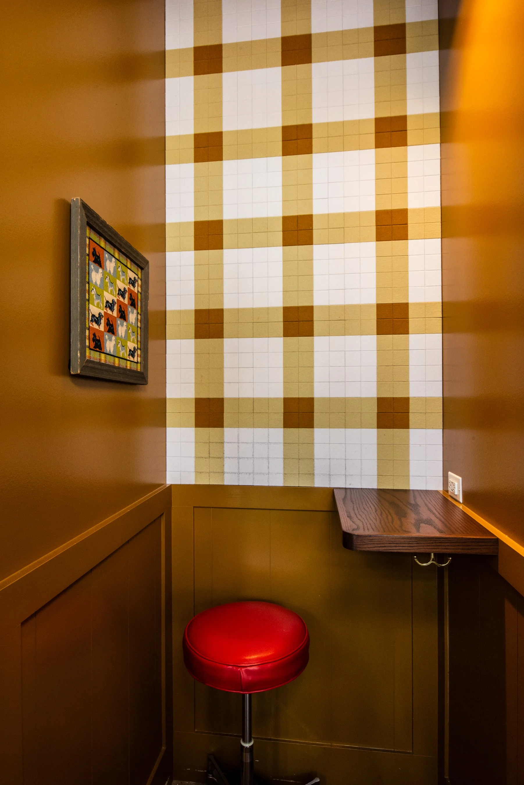 Layla and Ringo’s small booth nook with plaid tile wall, red stool, and wood ledge seating by Siren Betty Design
