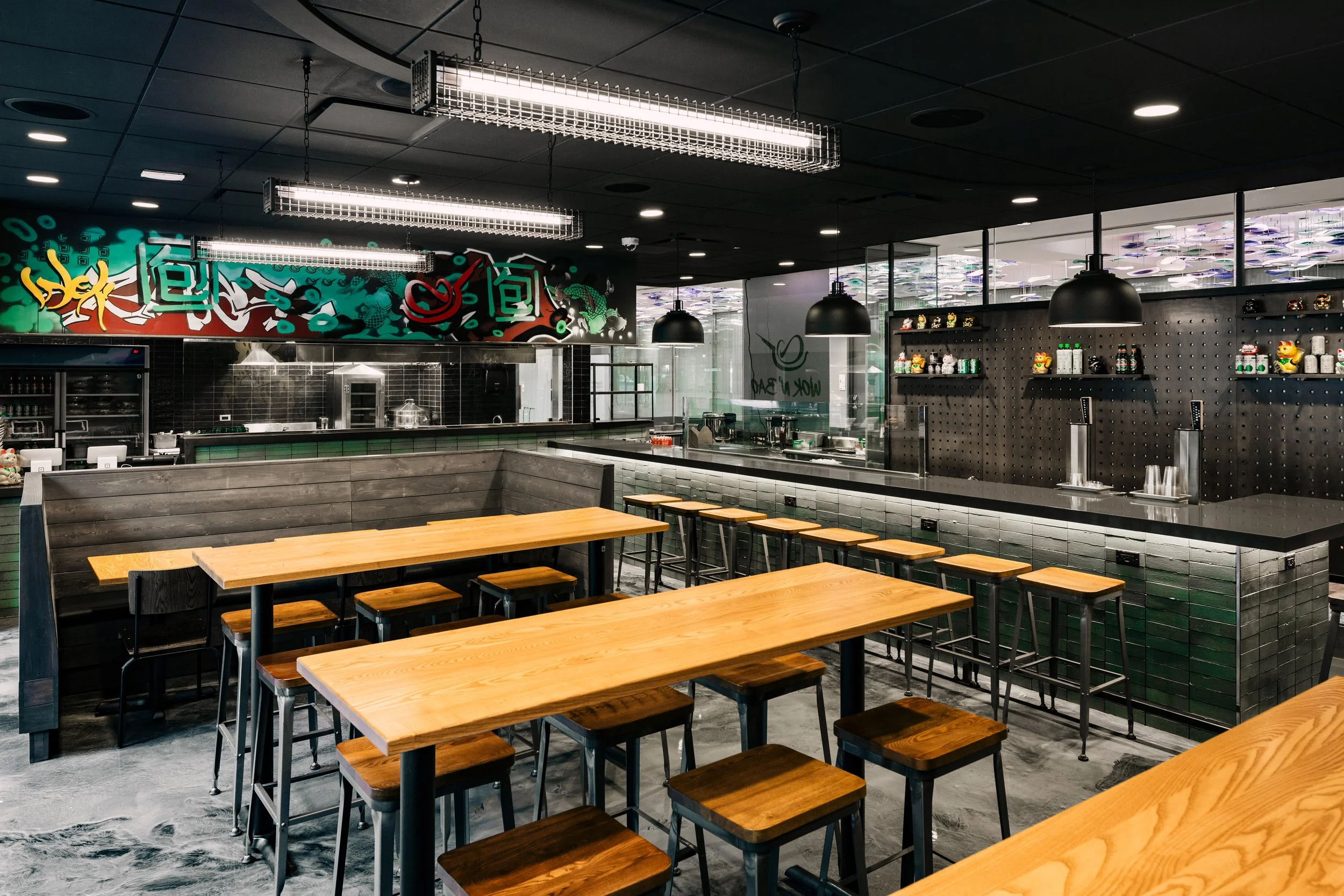 Modern dining at Wok N Bao in Chicago by Siren Betty Design, with graffiti accents, wood tables, and black pendant lights.