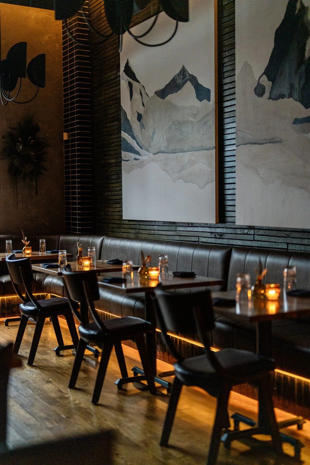 El Che restaurant interior by Siren Betty Design with mountain artwork, black leather banquettes, candlelit tables, and warm lighting.