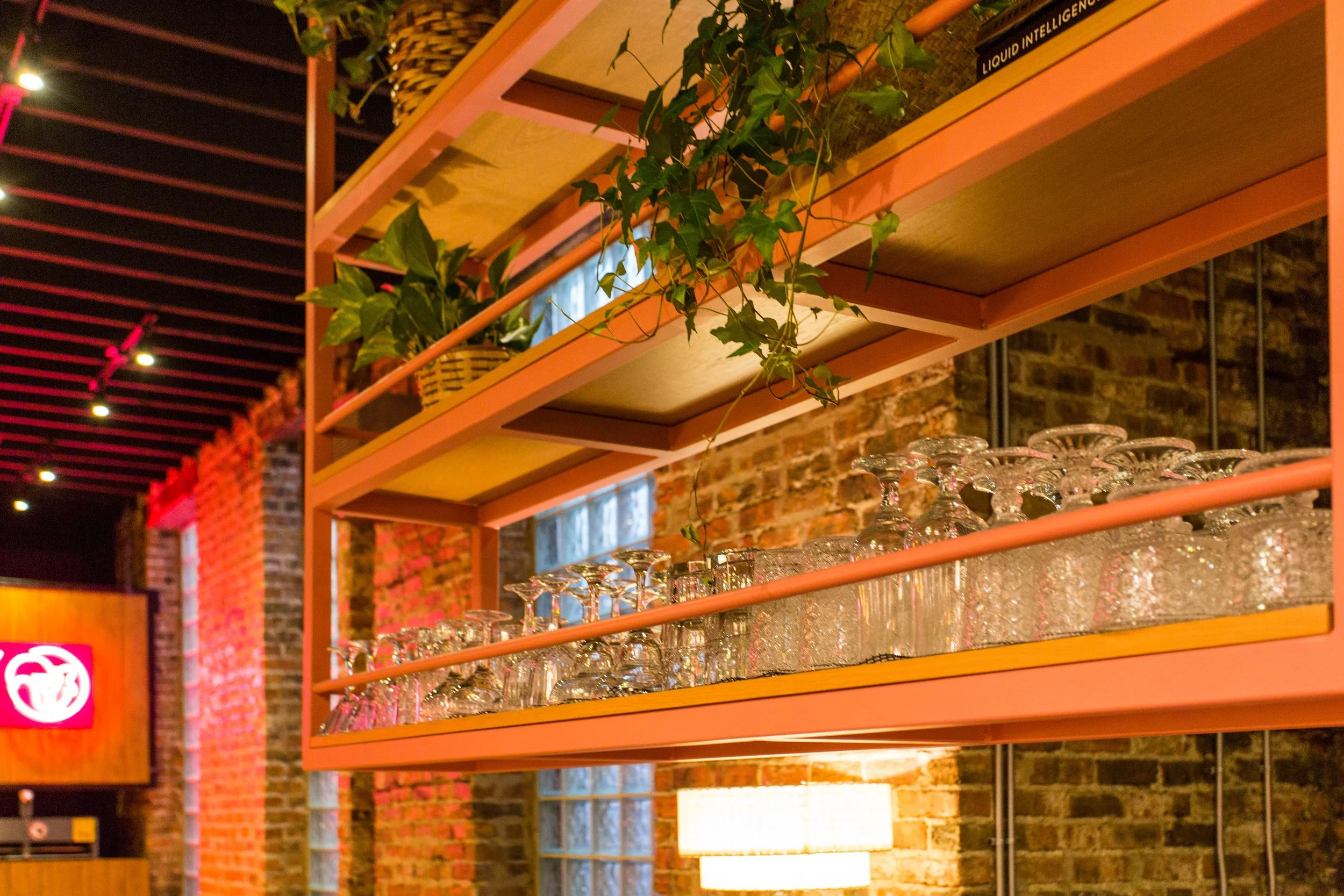 Pink Squirrel by Siren Betty Design, Chicago cocktail bar with hanging shelves stacked with glassware and lush greenery.
