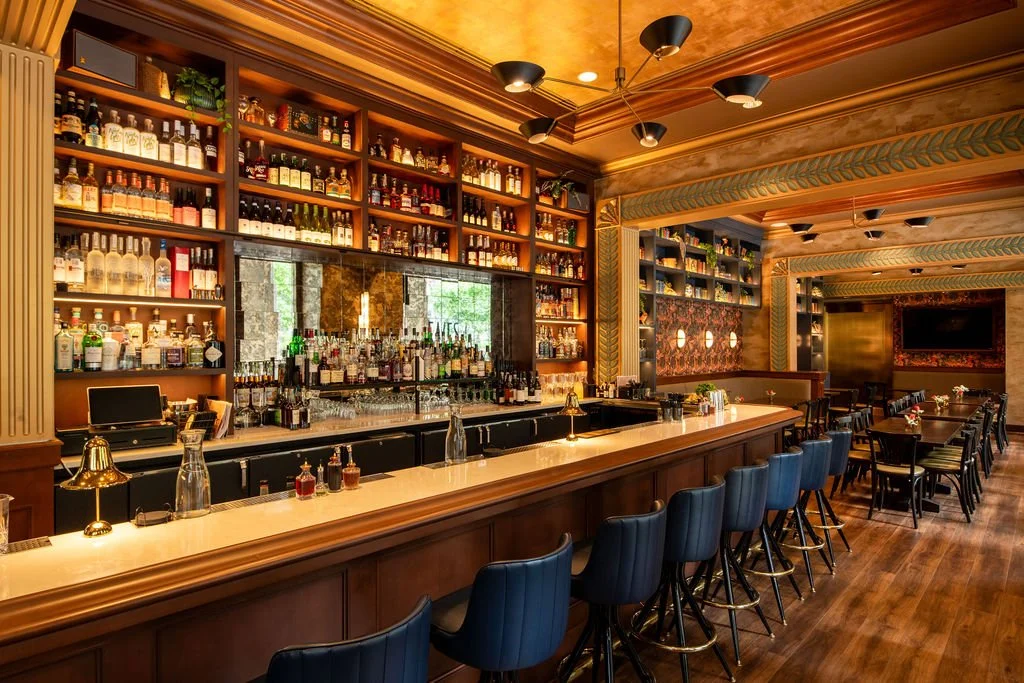Long Eaves bar with illuminated shelving, patterned walls and architectural trim by Siren Betty Design.