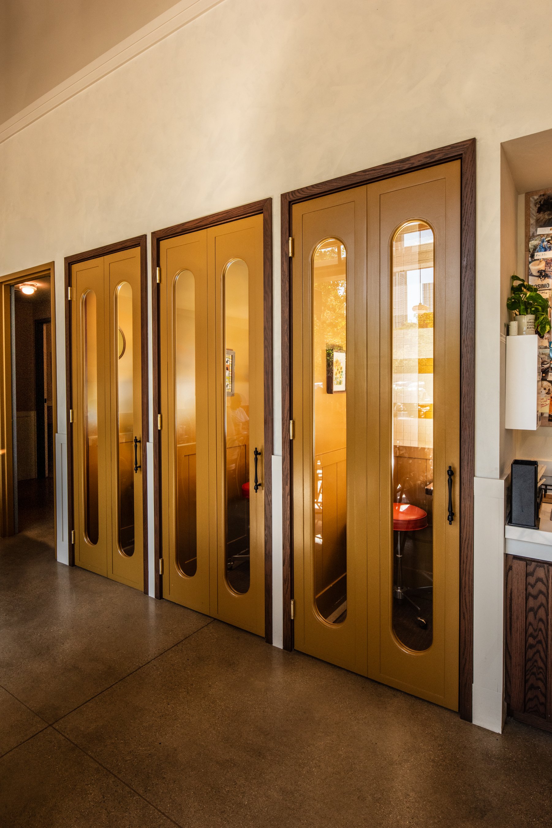 Layla and Ringo’s interior with mustard booth entrance doors, warm light, and wood trim detailing by Siren Betty Design
