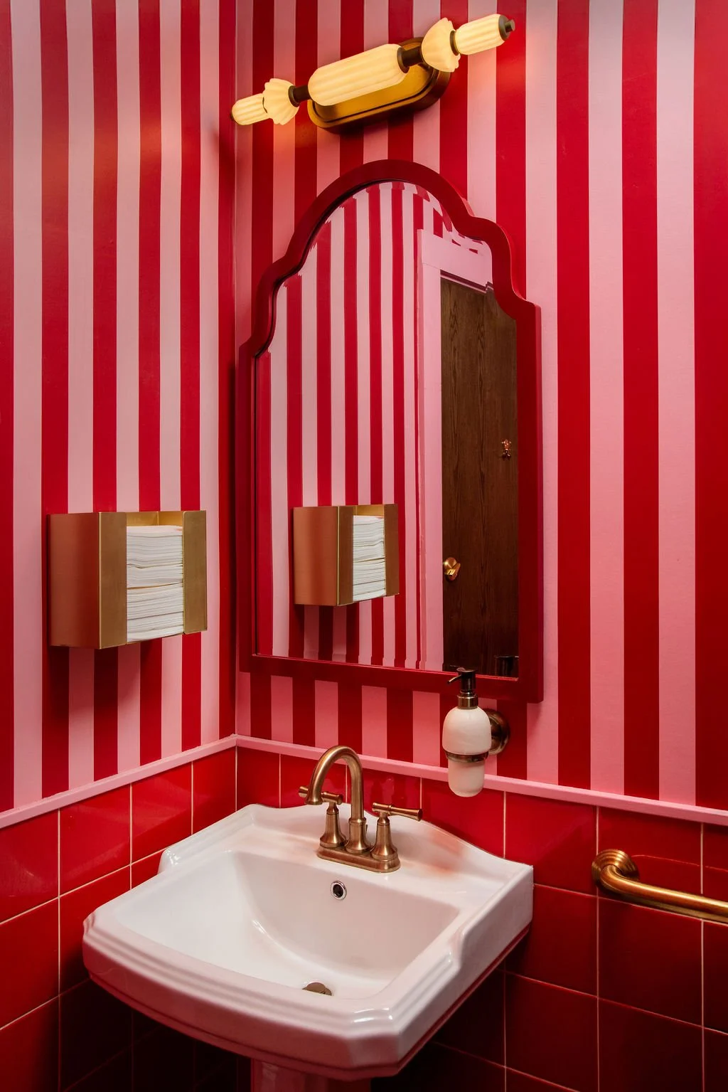 Red striped restroom vanity and mirror at Dimmi Dimmi by Siren Betty Design.