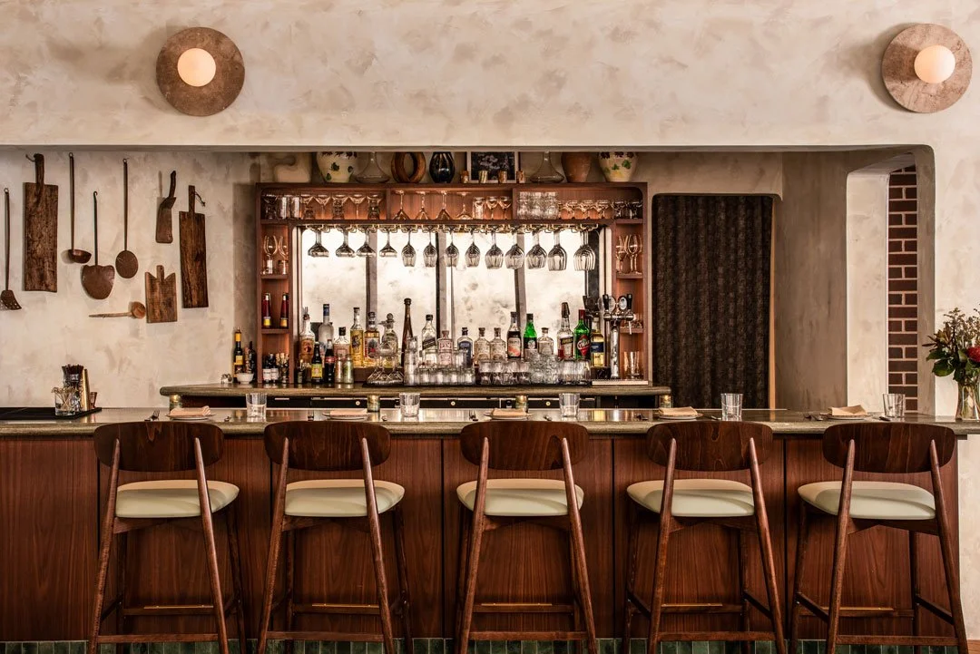 Custom walnut bar at Burl restaurant featuring sculptural lighting, textured plaster walls, and warm hospitality interiors by Siren Betty Design.