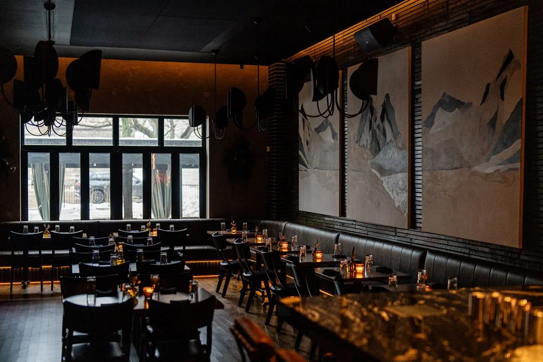 El Che restaurant interior by Siren Betty Design with charcoal brick, mountain artwork, leather banquettes, and candlelit tables.