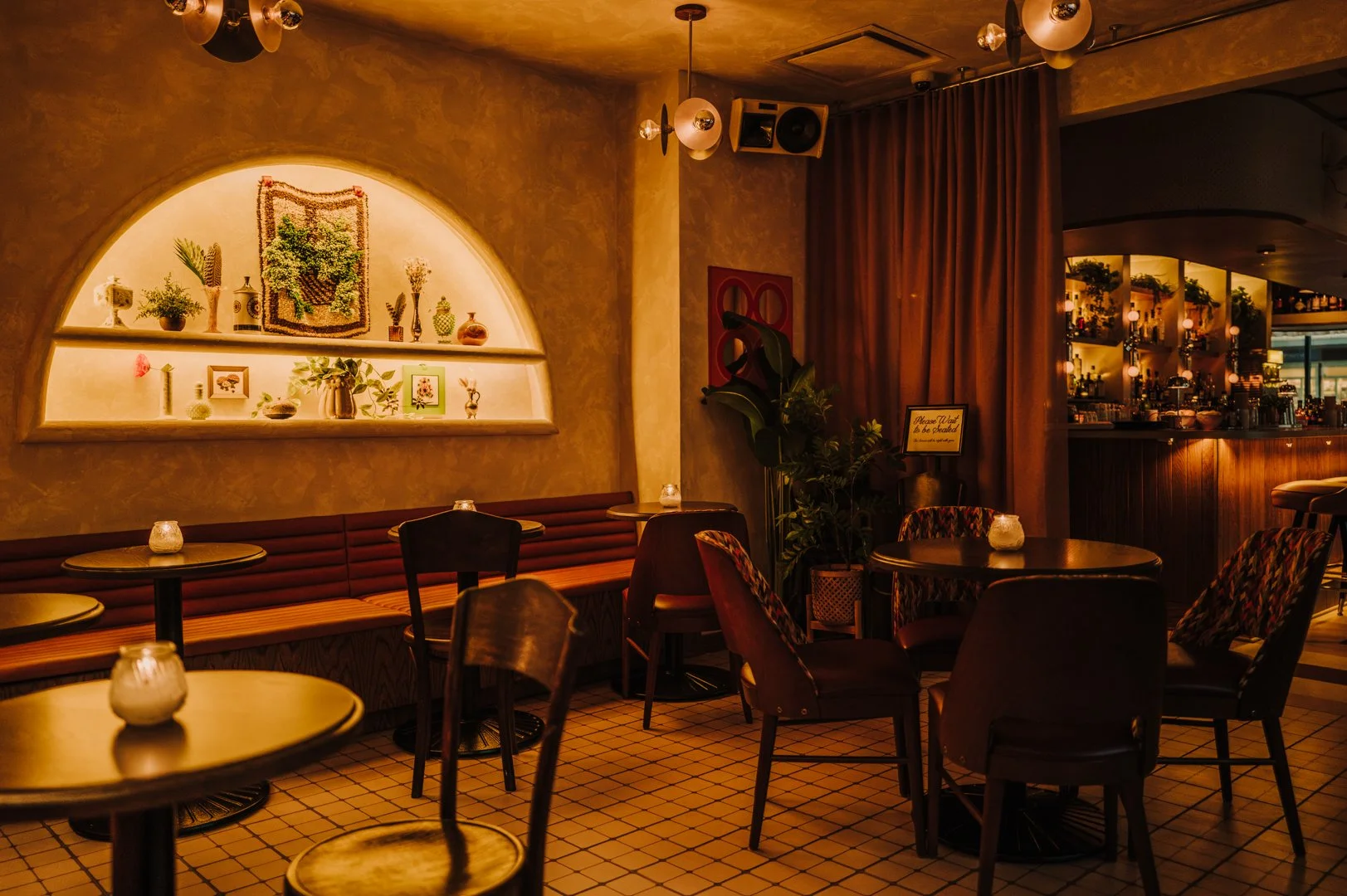 Double Fun interior featuring arched wall niche, banquette seating, and ambient lighting by Siren Betty Design.