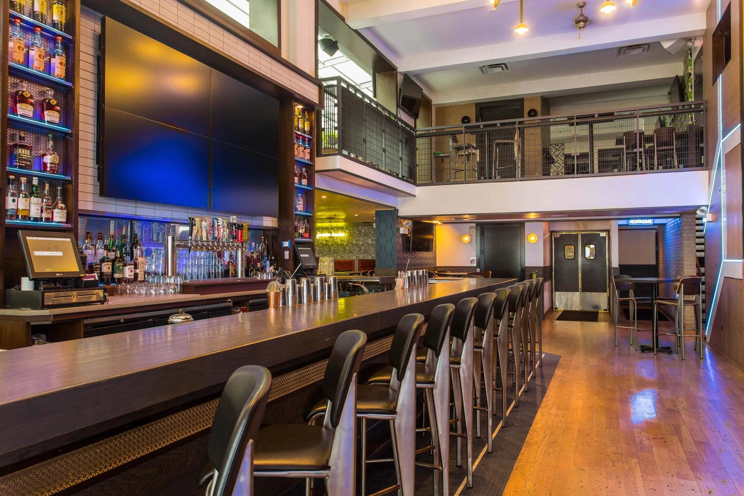 Benchmark by Siren Betty Design, contemporary double-height bar with industrial lighting and sleek seating.