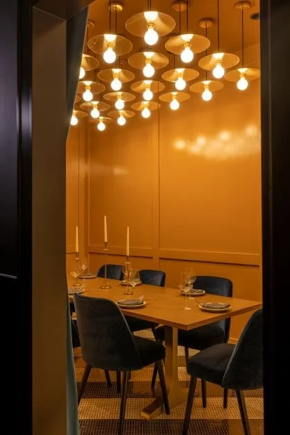 Private dining room at Hide & Seek by Siren Betty Design with gold walls, pendant lighting, and plush blue velvet seating.