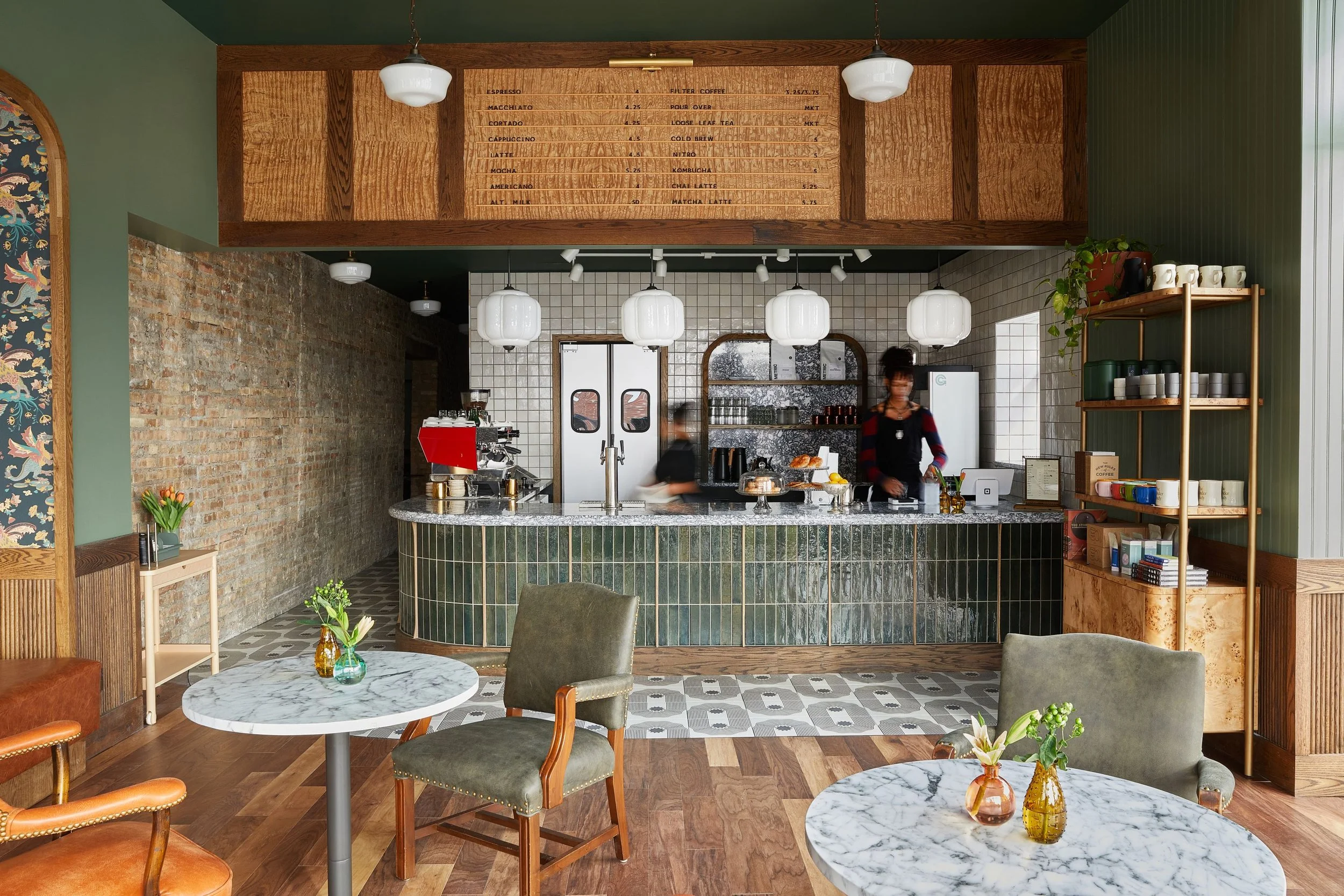 The Understudy café by Siren Betty Design features a green tile coffee bar, marble tables, and an exposed brick wall.