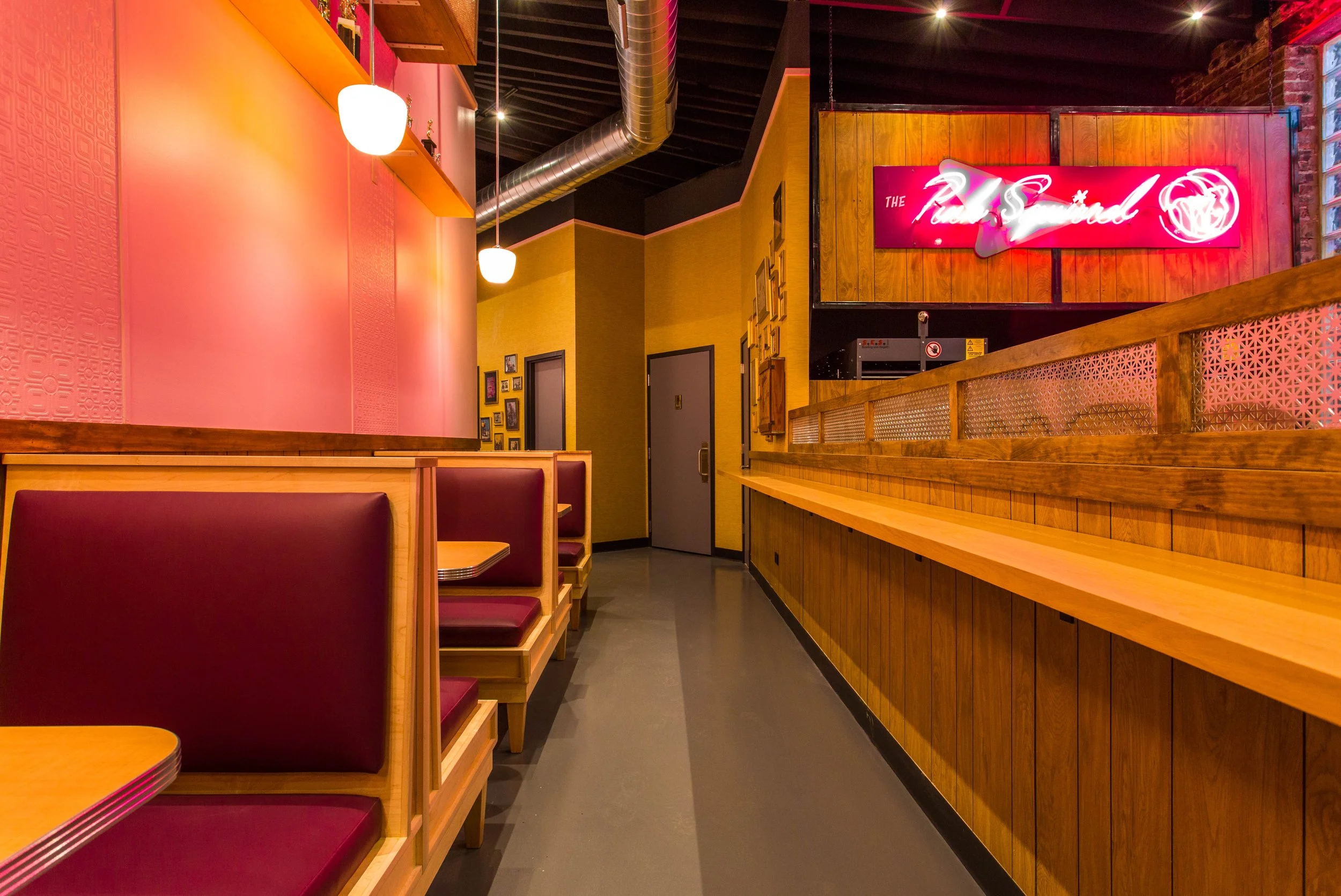 Pink Squirrel by Siren Betty Design, Chicago cocktail bar featuring pink booths, neon glow, and warm wood tones.