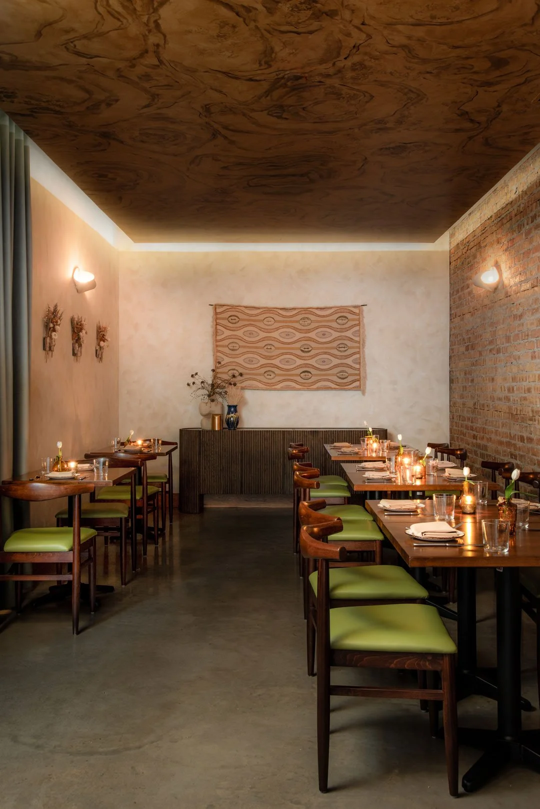 Intimate dining room at Burl with an illuminated burlwood ceiling, exposed brick, textile art, and interiors by Siren Betty Design.