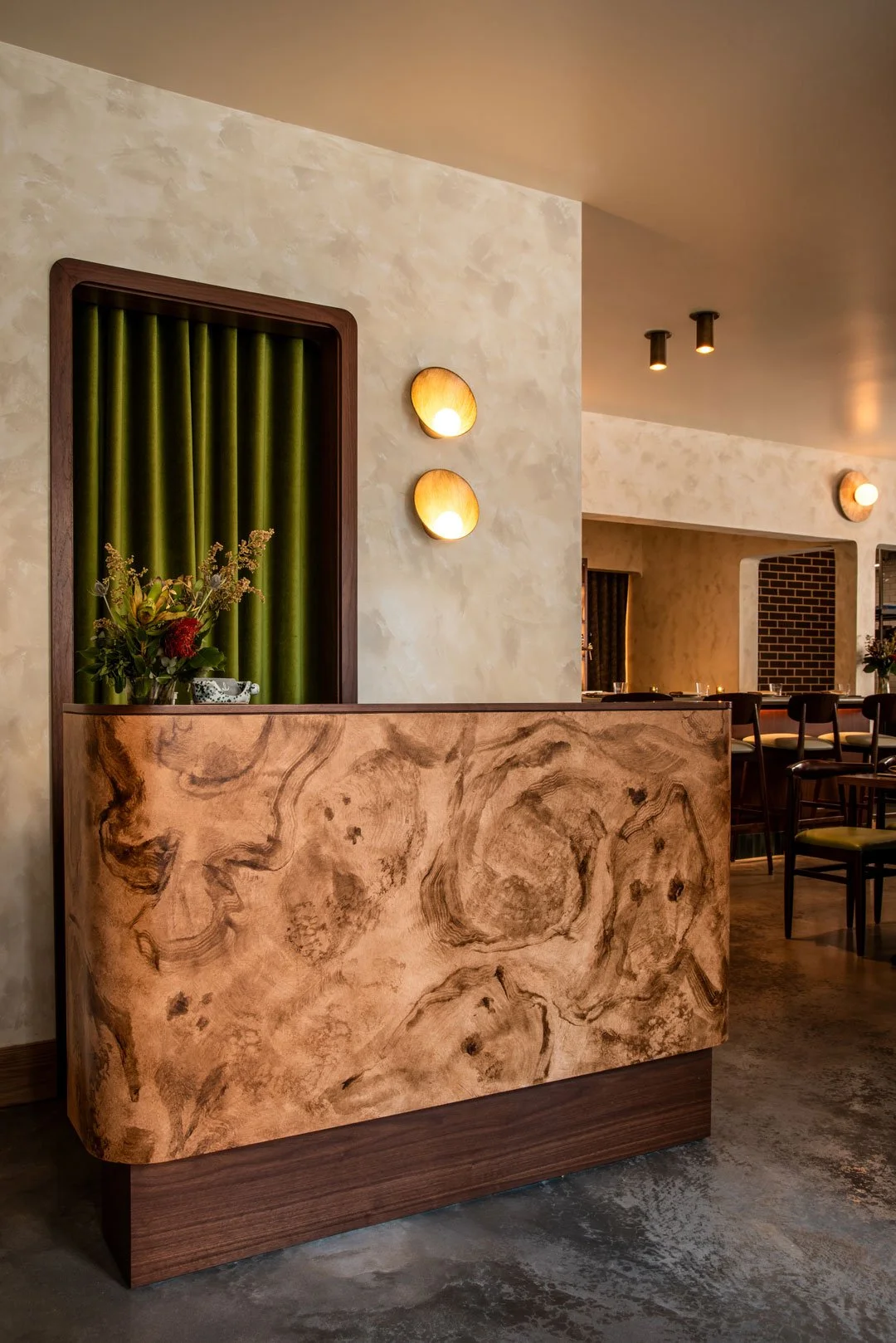 Burlwood host stand at Burl featuring olive velvet drapery, textured plaster walls, and sculptural lighting by Siren Betty Design.