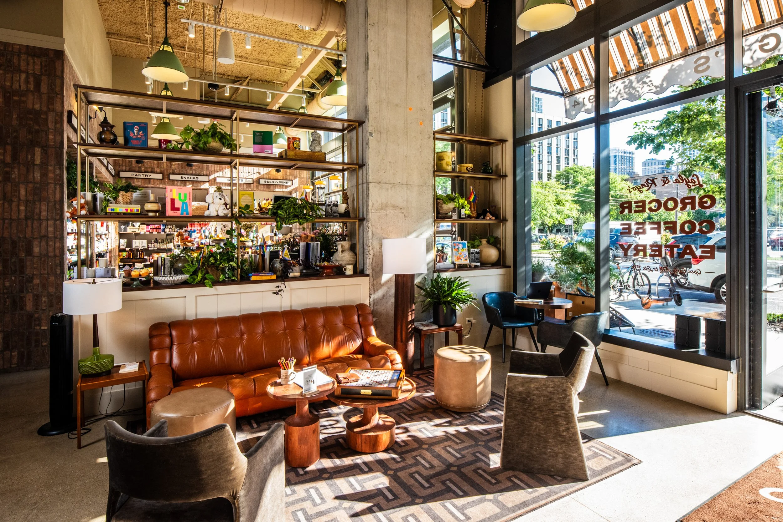 Layla and Ringo’s lounge with leather sofa, open shelving, café tables, and bright window light by Siren Betty Design