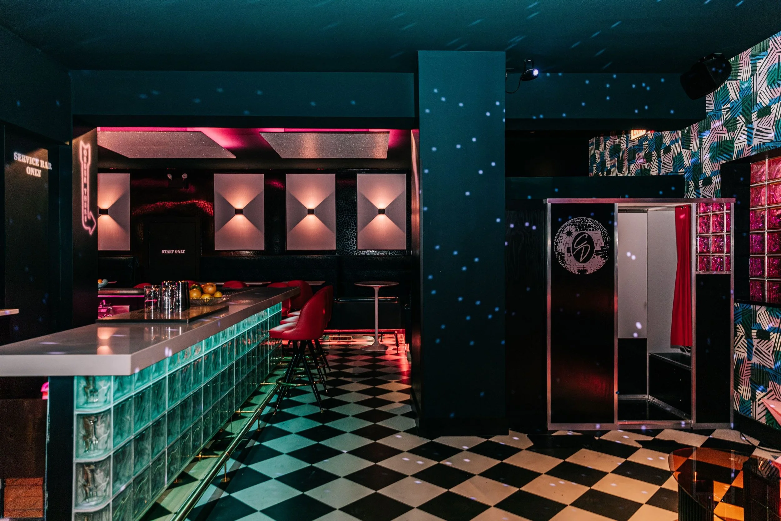 Common Decency by Siren Betty Design showcases the bar, photo booth, and checkered floors with glowing pink LED lighting.