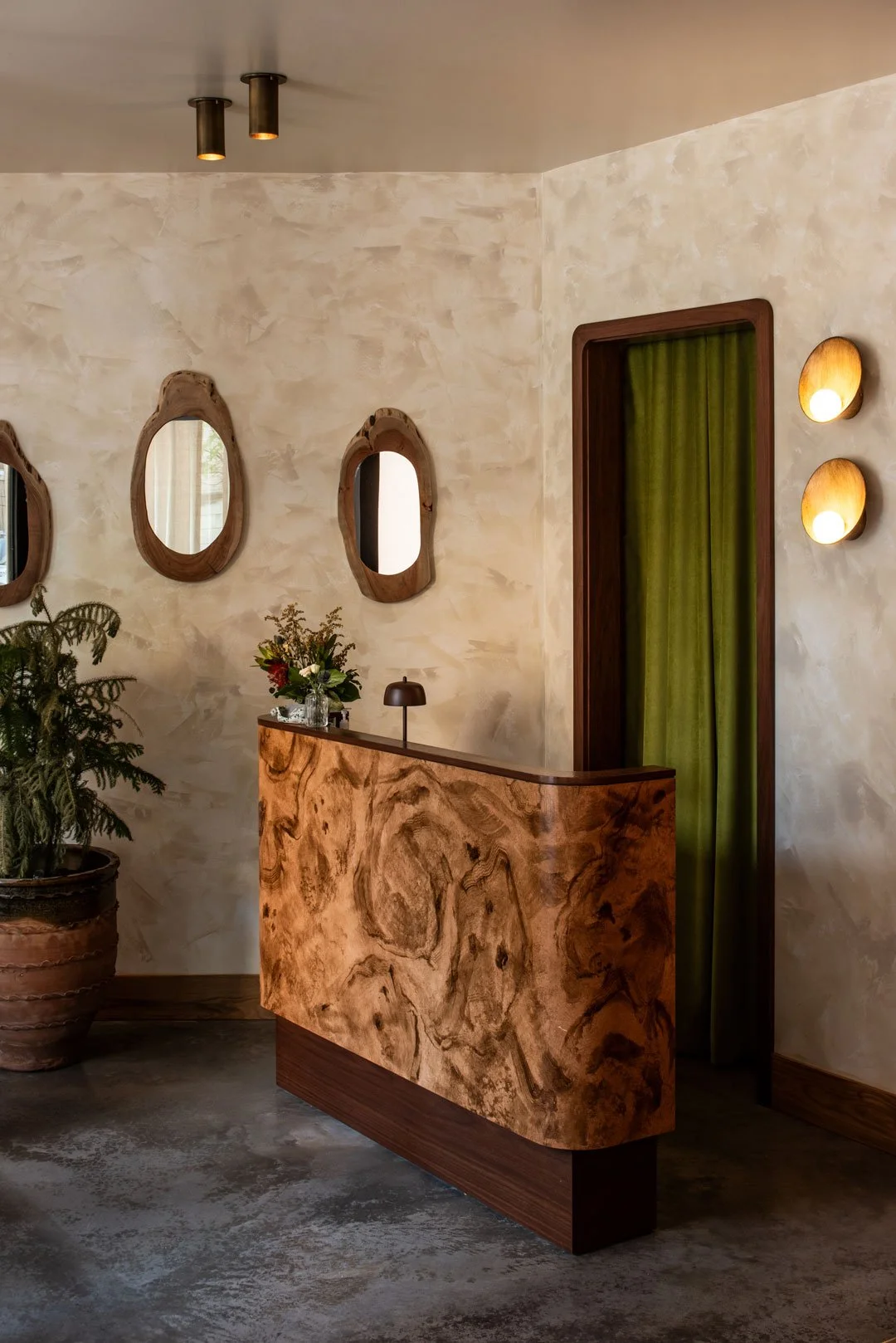 Burl restaurant entry with a custom burlwood host stand, organic wood mirrors, olive drapery, and hospitality design by Siren Betty Design.