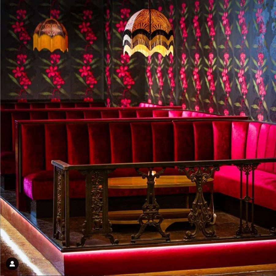 Velvet booths and floral wallpaper in Untitled Supper Club by Siren Betty Design, glowing with warm, moody lighting.