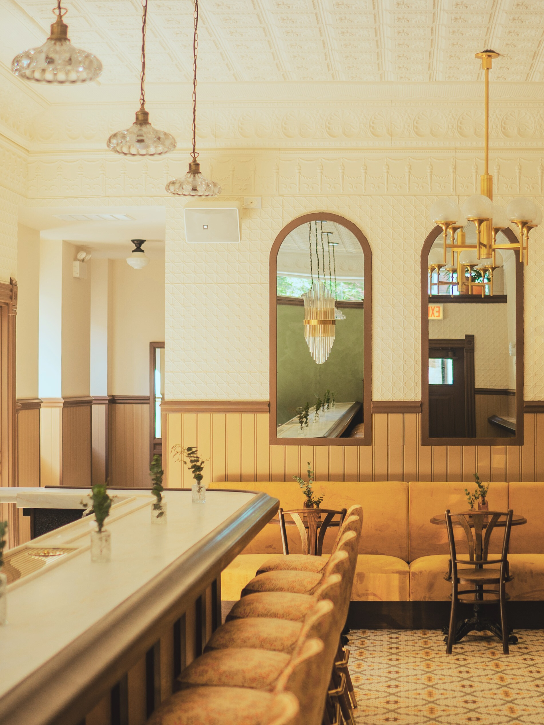 Warm-toned bar seating at The High-Lo by Siren Betty Design, featuring marble countertops, vintage lighting, and patterned tile.