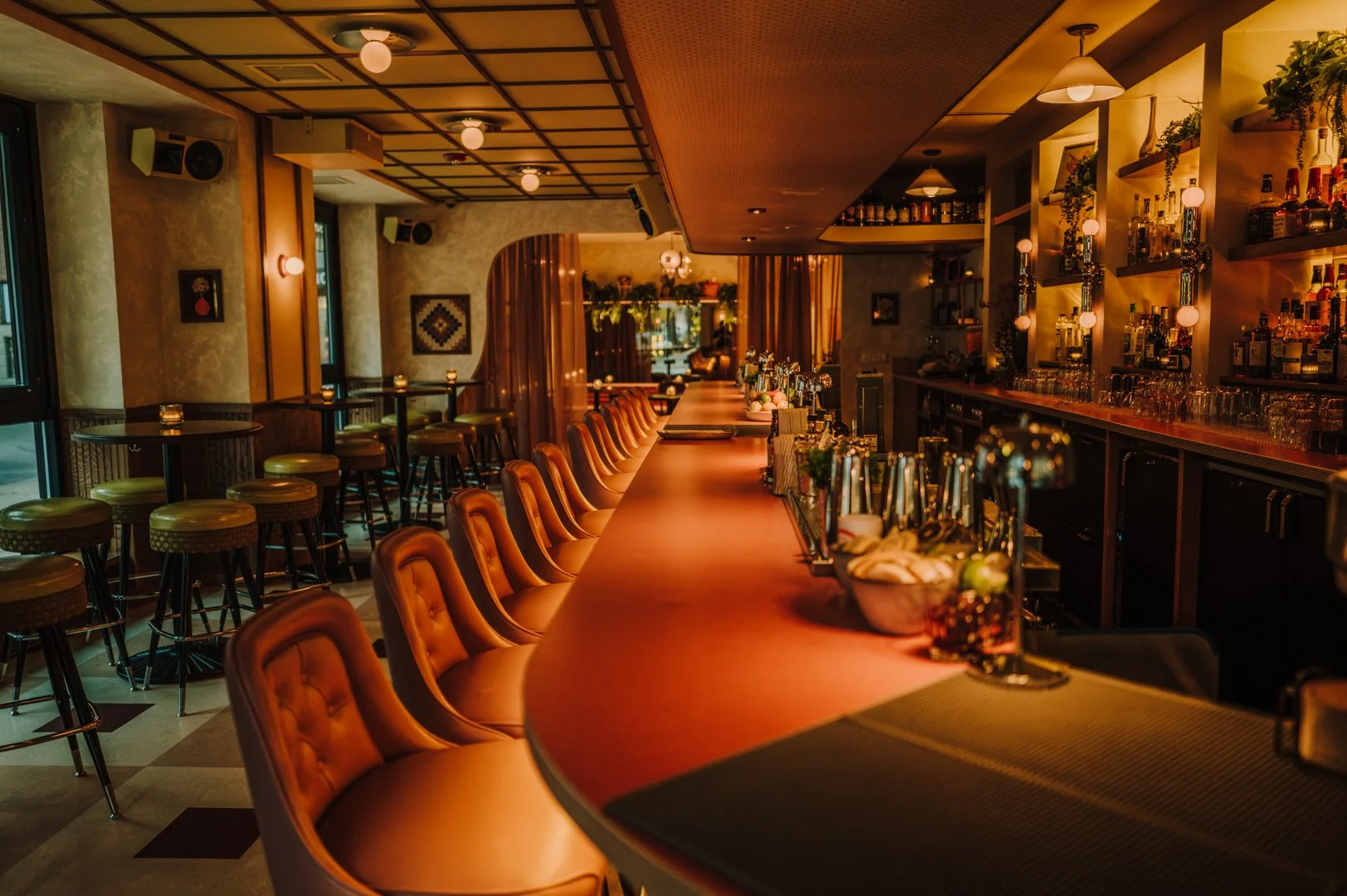 Double Fun bar interior with curved wood bar, leather stools, and warm lighting by Siren Betty Design.