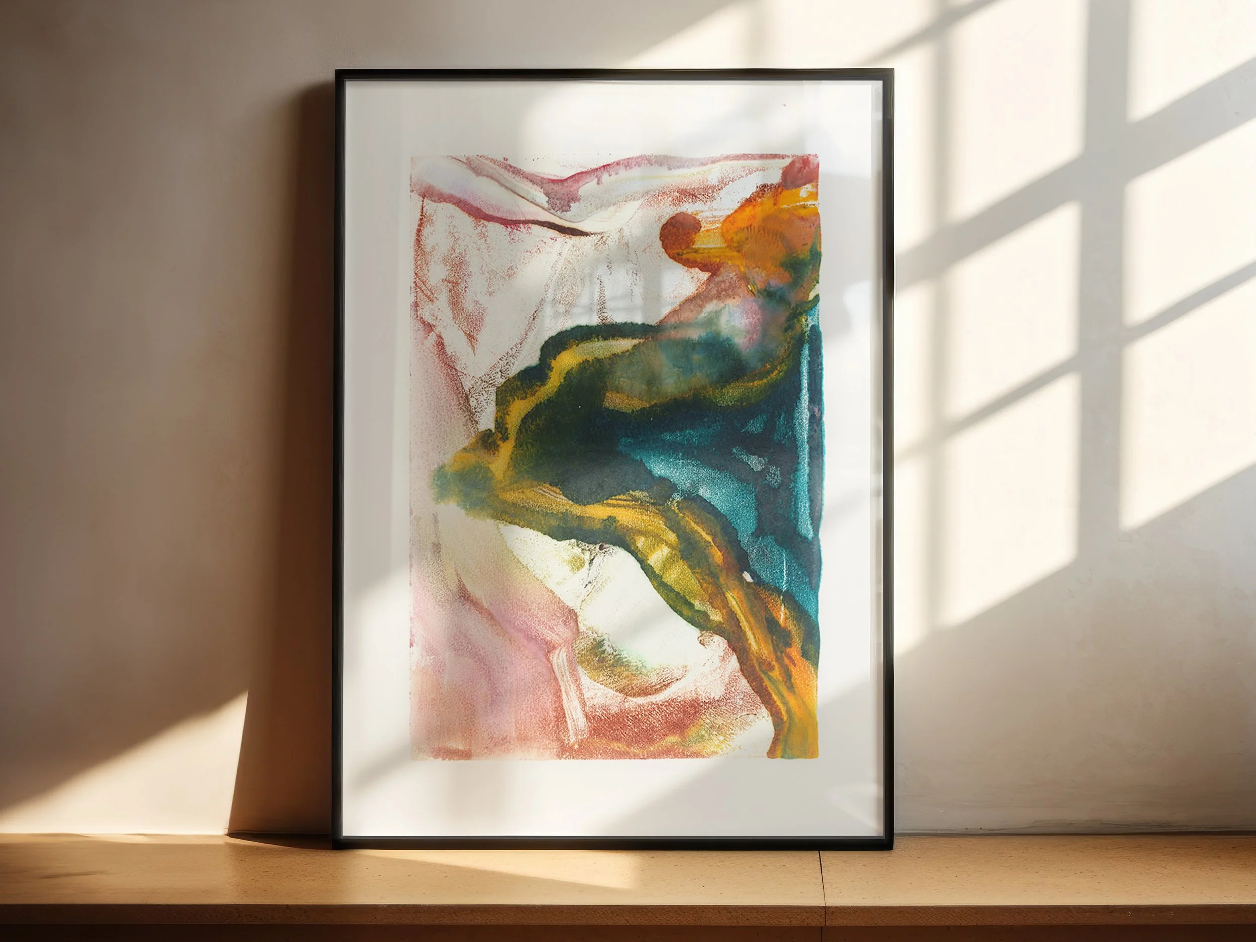Bloom by Melissa McGill displayed in a black frame on a sunlit wood shelf, with saturated turquoise and green forms surrounded by yellow, orange, rust, and pink.