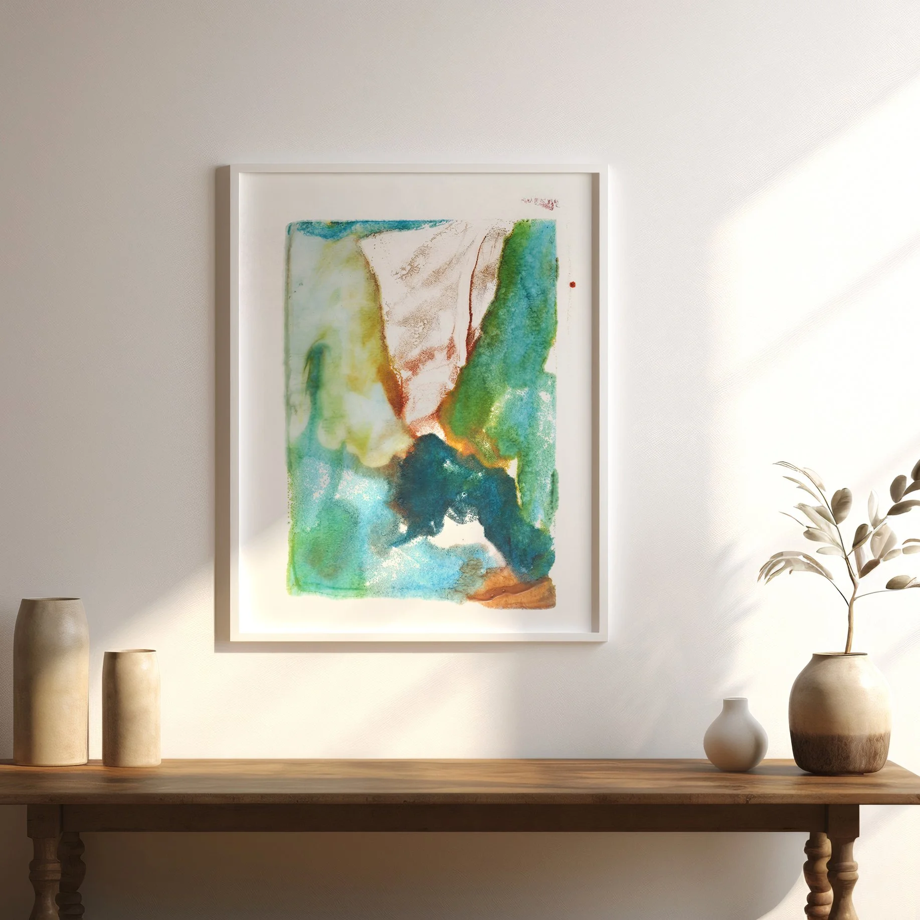 Confluence by Melissa McGill, abstract encaustic monotype on abaca paper with turquoise, green, deep blue, and warm earth tones, displayed in a white frame above a wood table.