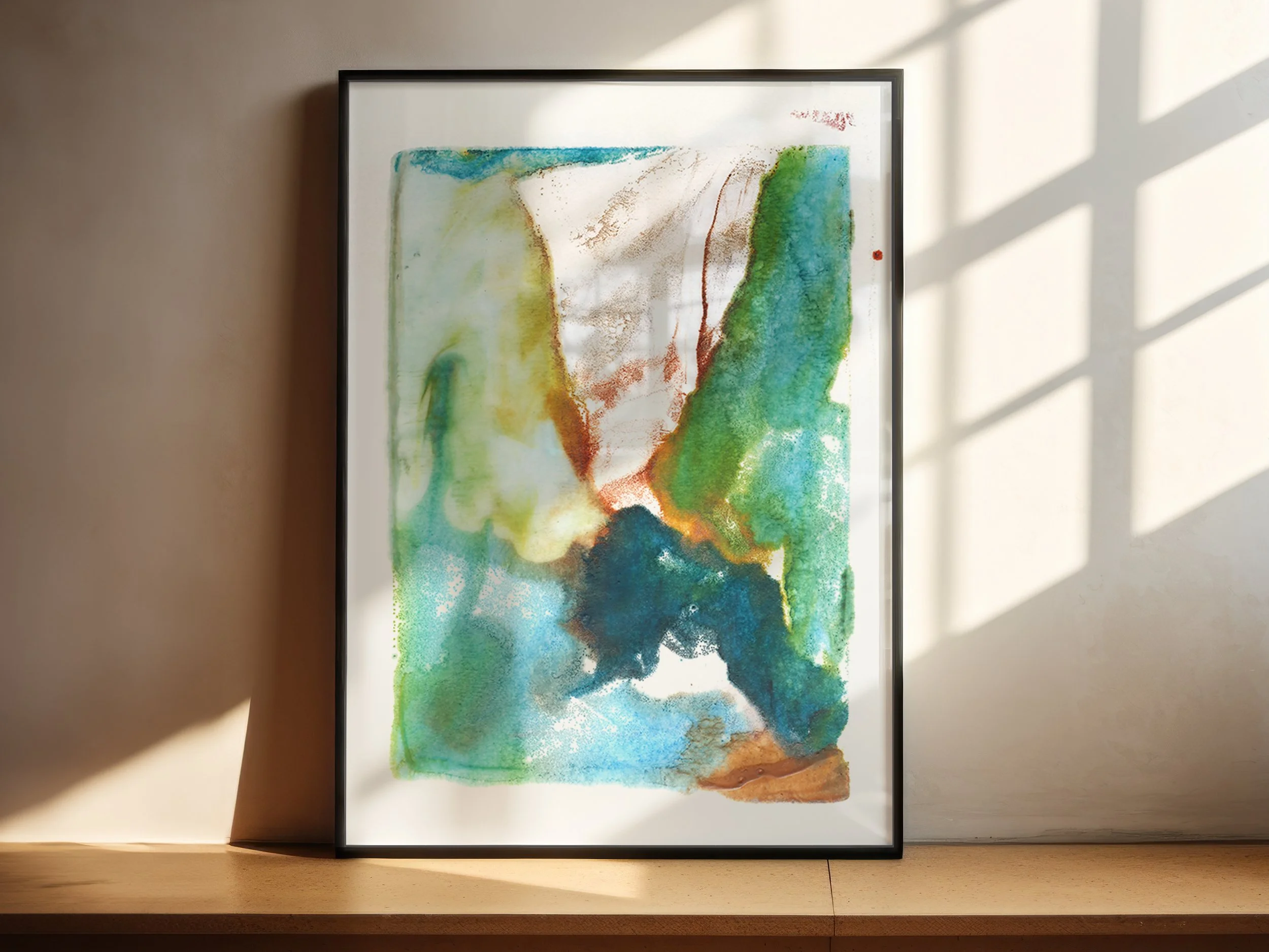 Confluence by Melissa McGill displayed in a black frame on a sunlit shelf, showing layered turquoise, green, blue, and ochre forms around a light central passage.