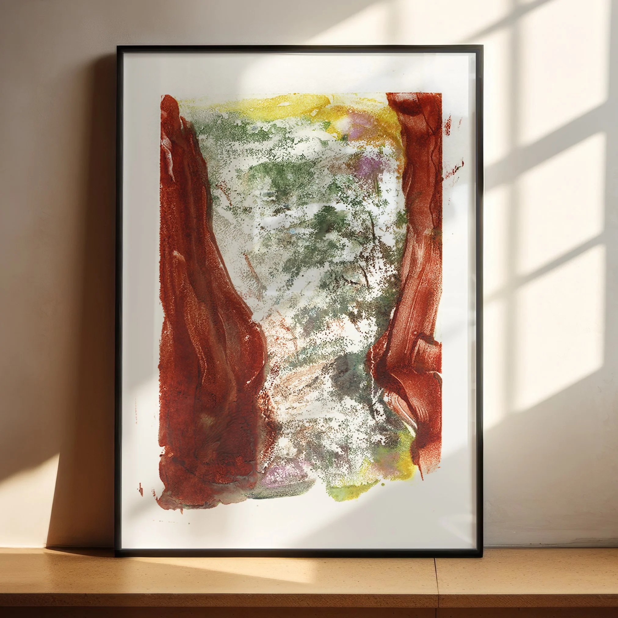 Understory by Melissa McGill displayed in a black frame on a sunlit wood shelf, with deep rust-red forms enclosing a mottled green interior.