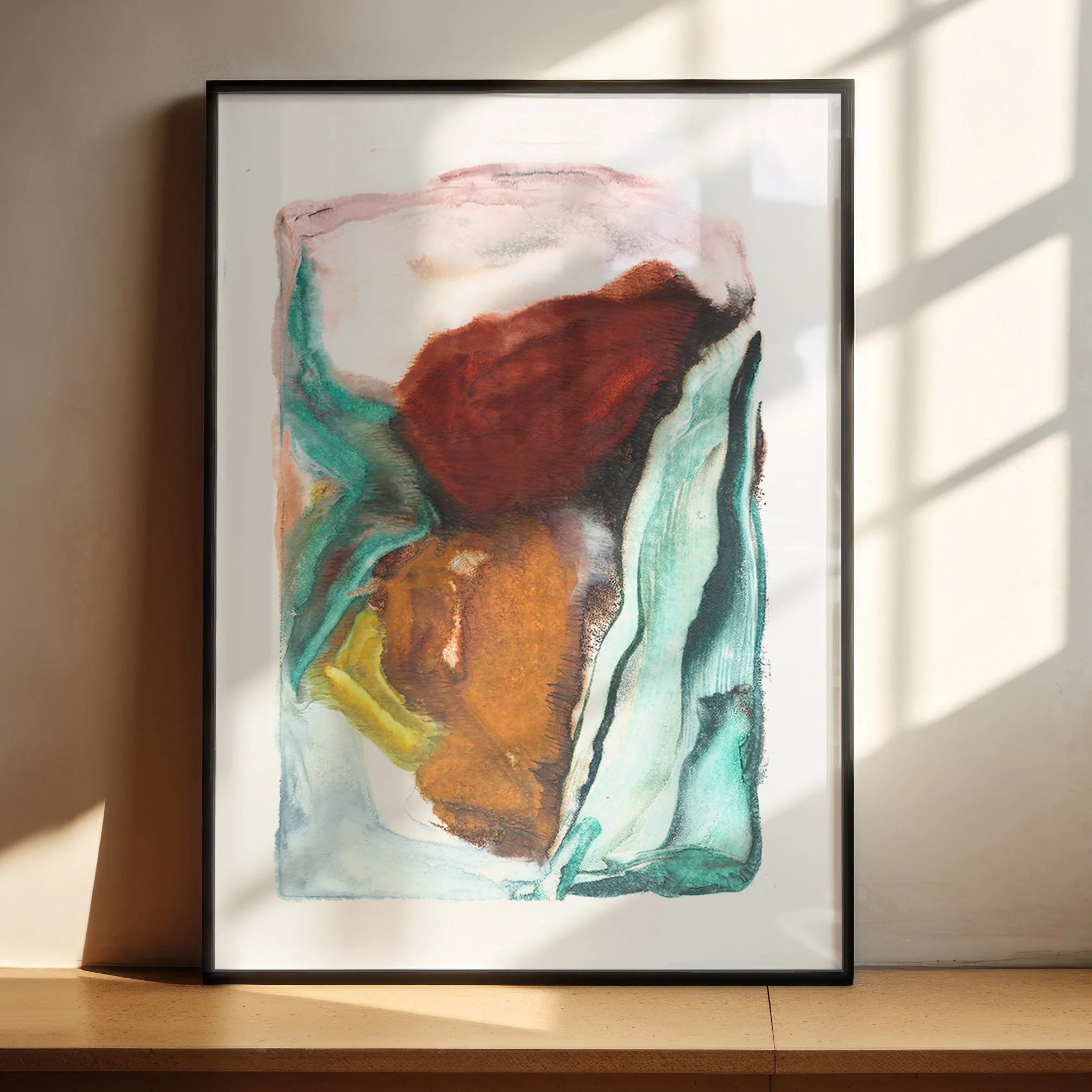 Basin by Melissa McGill displayed in a black frame on a sunlit wooden shelf, showing a central rust-red and ochre mass enclosed by flowing turquoise and green passages.