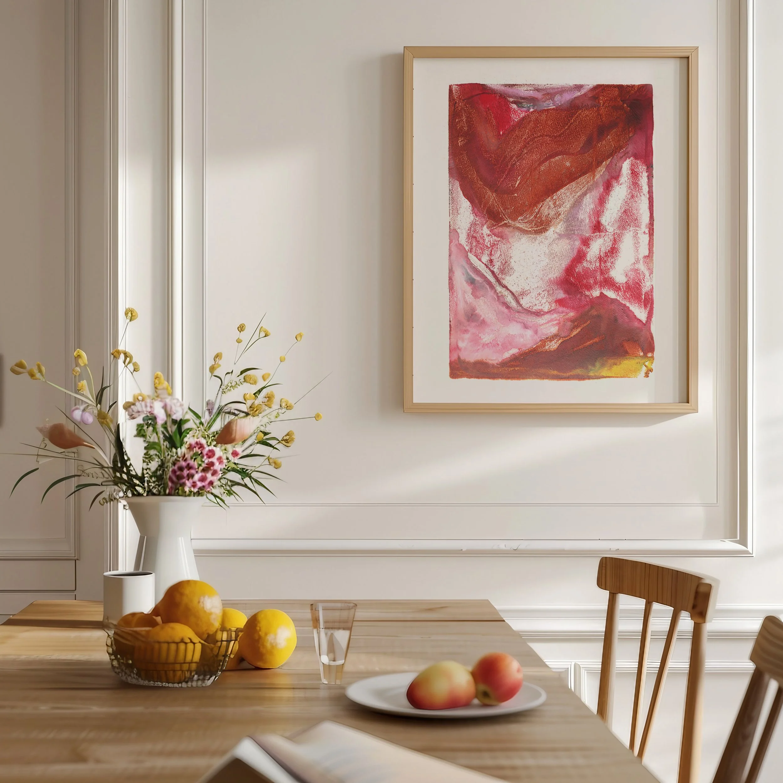 Thermal by Melissa McGill displayed in a natural wood frame above a dining table with flowers and fruit, showing an abstract composition of rust, crimson, pink, and orange.