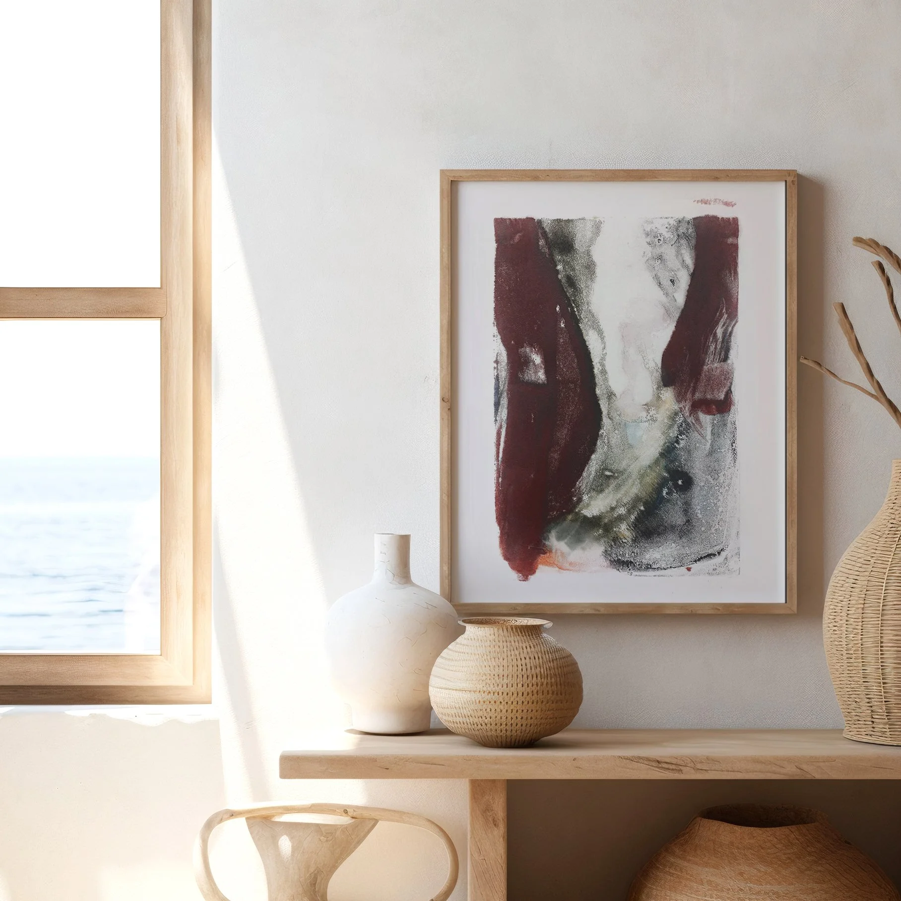 Ravine by Melissa McGill displayed in a natural wood frame above a wooden console with ceramic and woven vessels, beside a sunlit window.