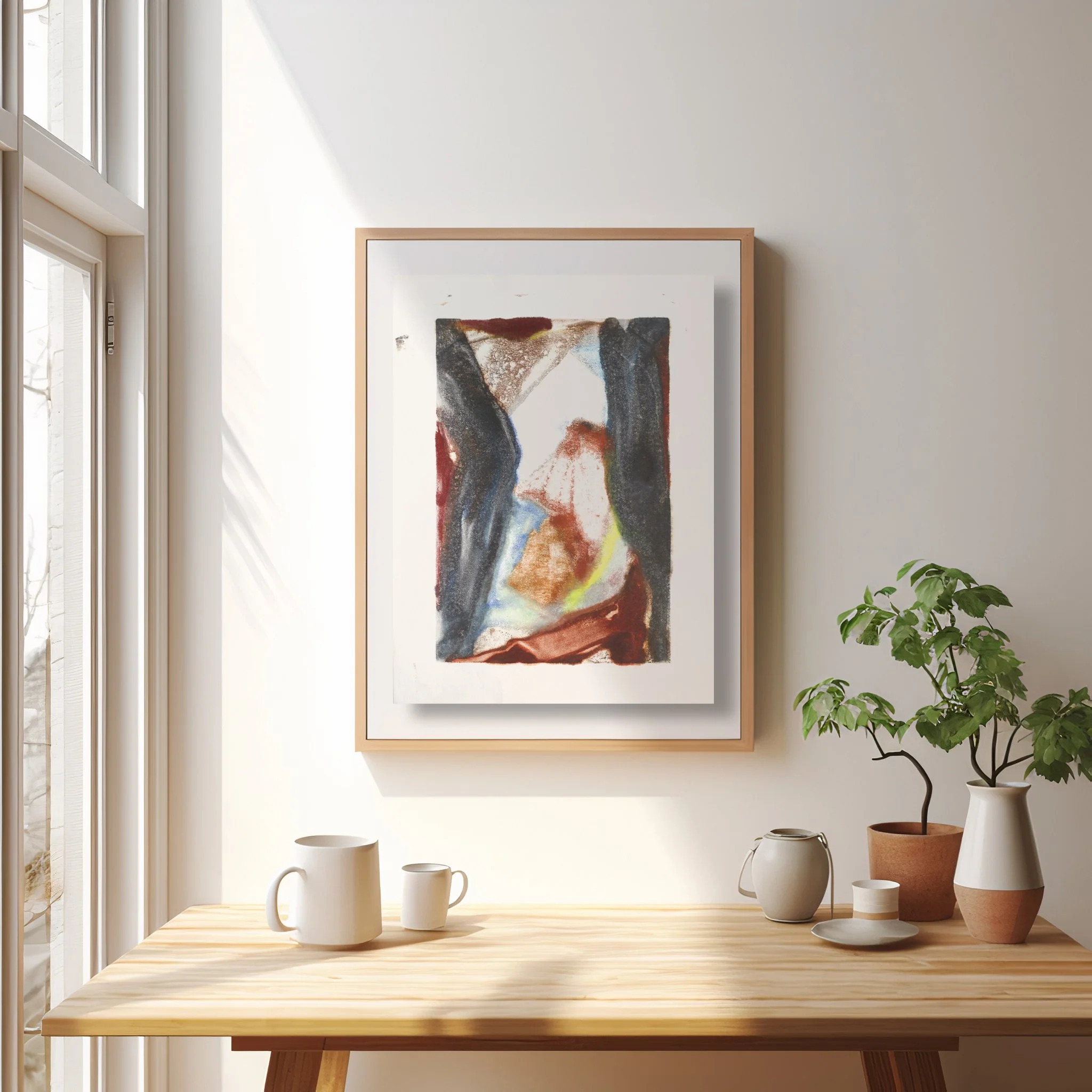 Divide by Melissa McGill displayed in a natural wood frame above a wood table in a sunlit interior, with two dark forms enclosing a lighter central passage.