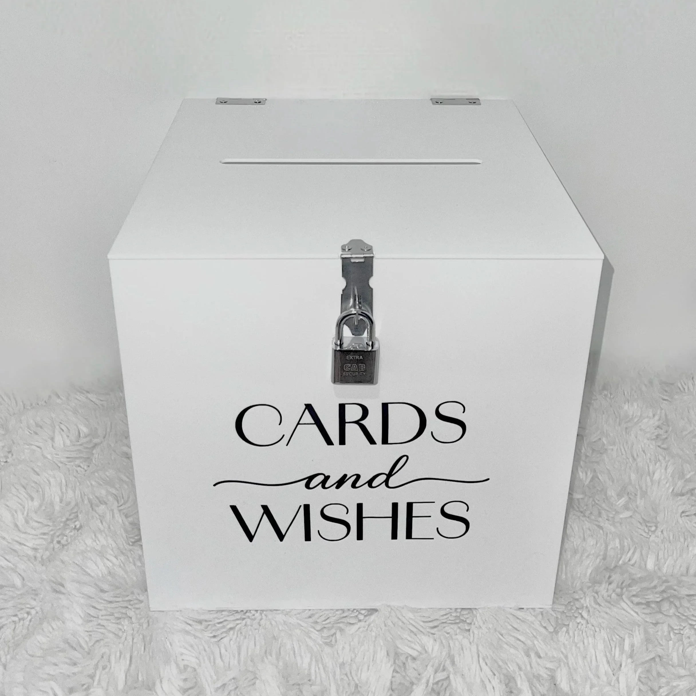 White box labeled 'CARDS' with a latch and lock, placed on a white furry surface.