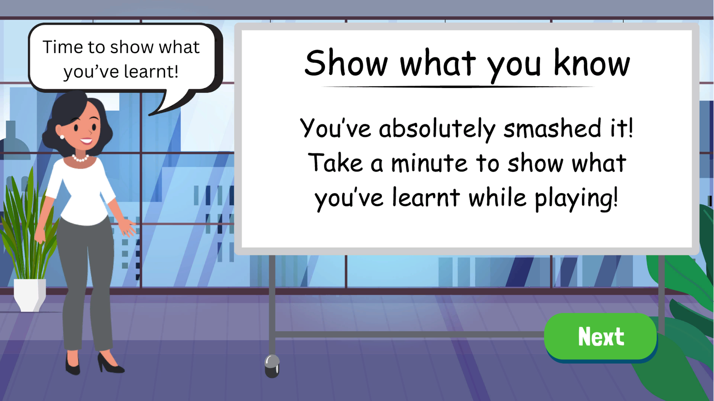 A woman with black hair, dressed in a white blouse and gray pants, is standing in an office or classroom with large windows and plants in the background. She is smiling and pointing to a whiteboard that displays instructions for a learning activity.