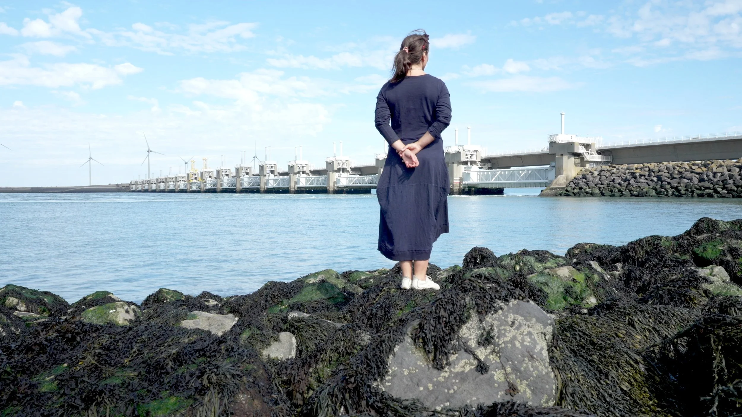 still from Waterwake, Valentina standing in front of the Oosterscheldekering