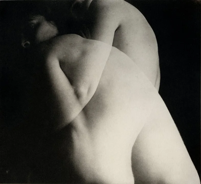 Black and white photo of two people embracing passionately, their bodies intertwined.