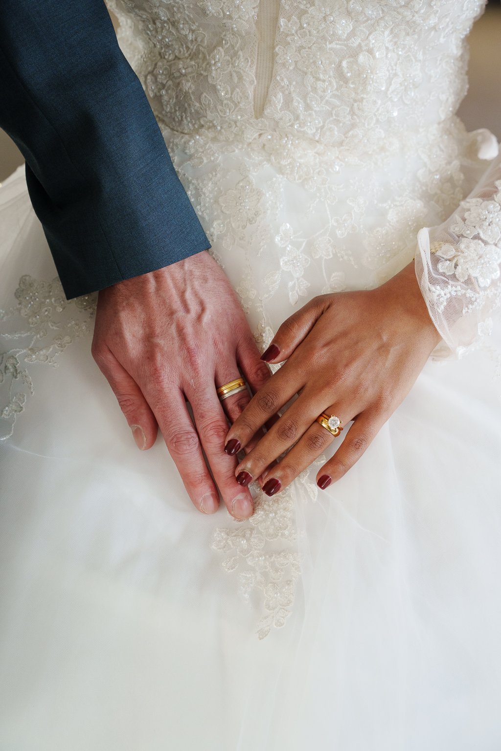 Close-up of a bride and groom holding hands, showing wedding rings at Aeroe City Hall.