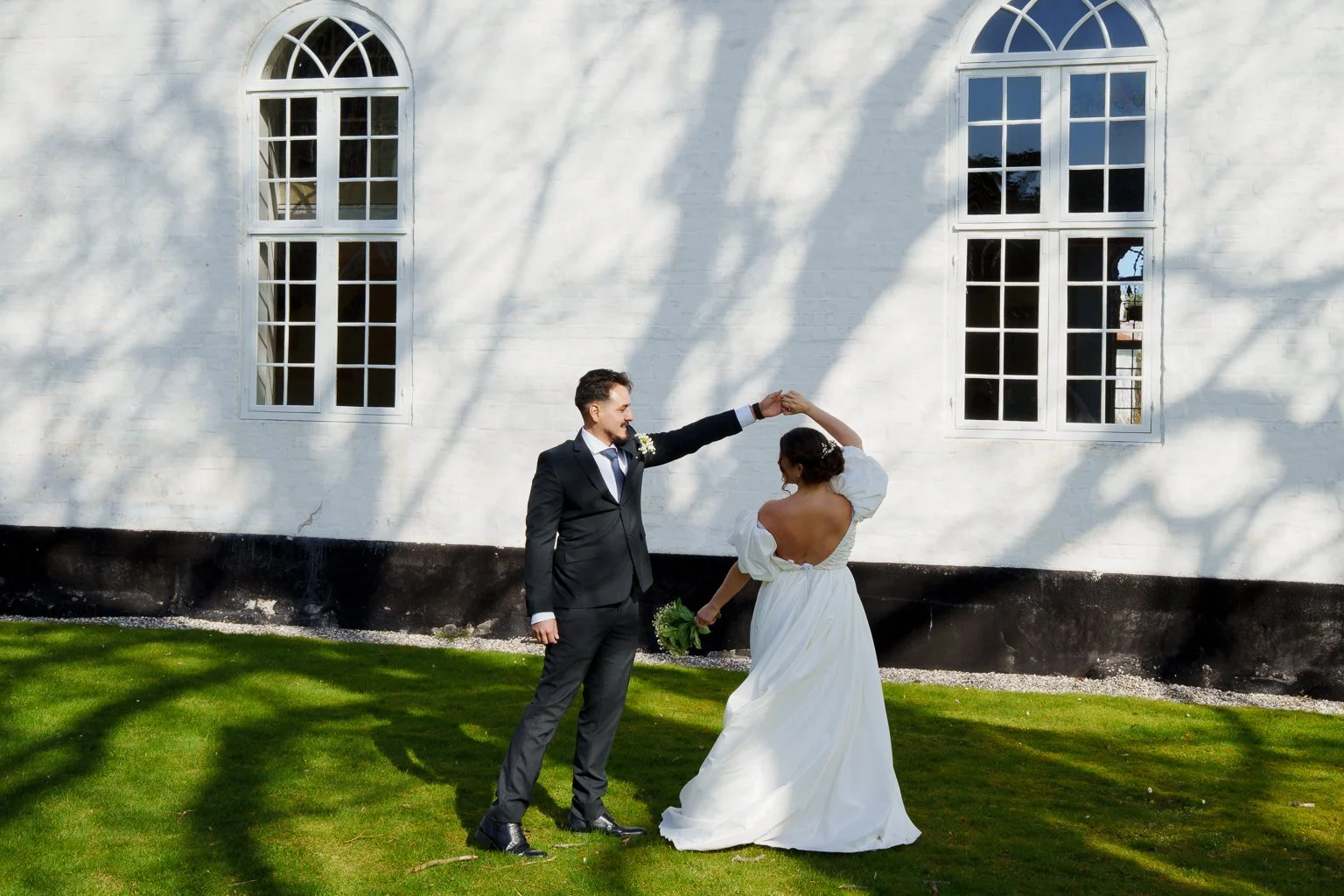 Wedding photo of couple dancing in front of church in Ærøskøbing.