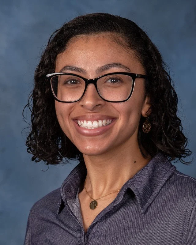 A shield emblem with a gold fish symbol above a column, surrounded by gray laurel branches.