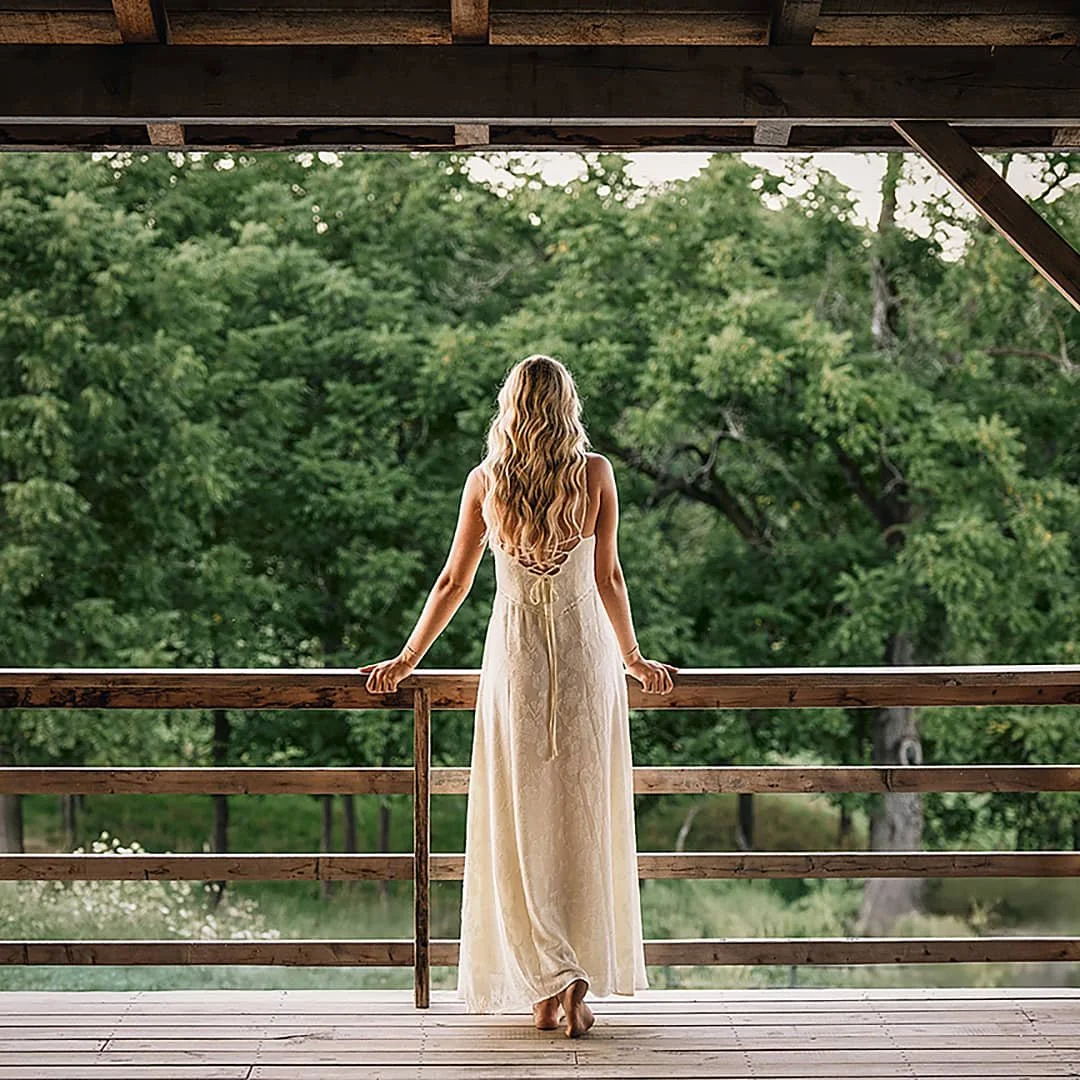 woman in flowing white dress outdoor lifestyle commercial photography on rustic wooden deck